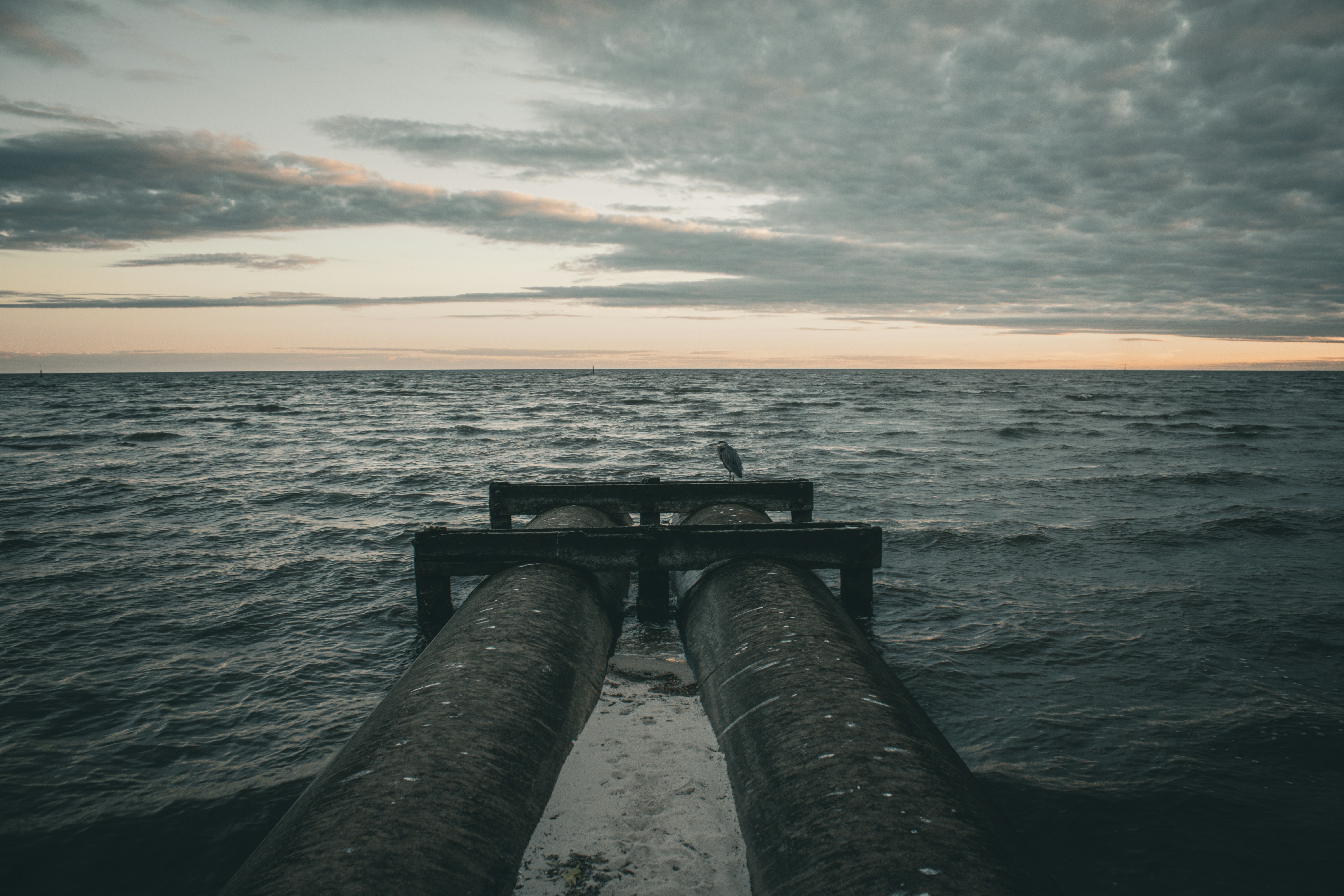 Two large pipes extend into the choppy ocean water.