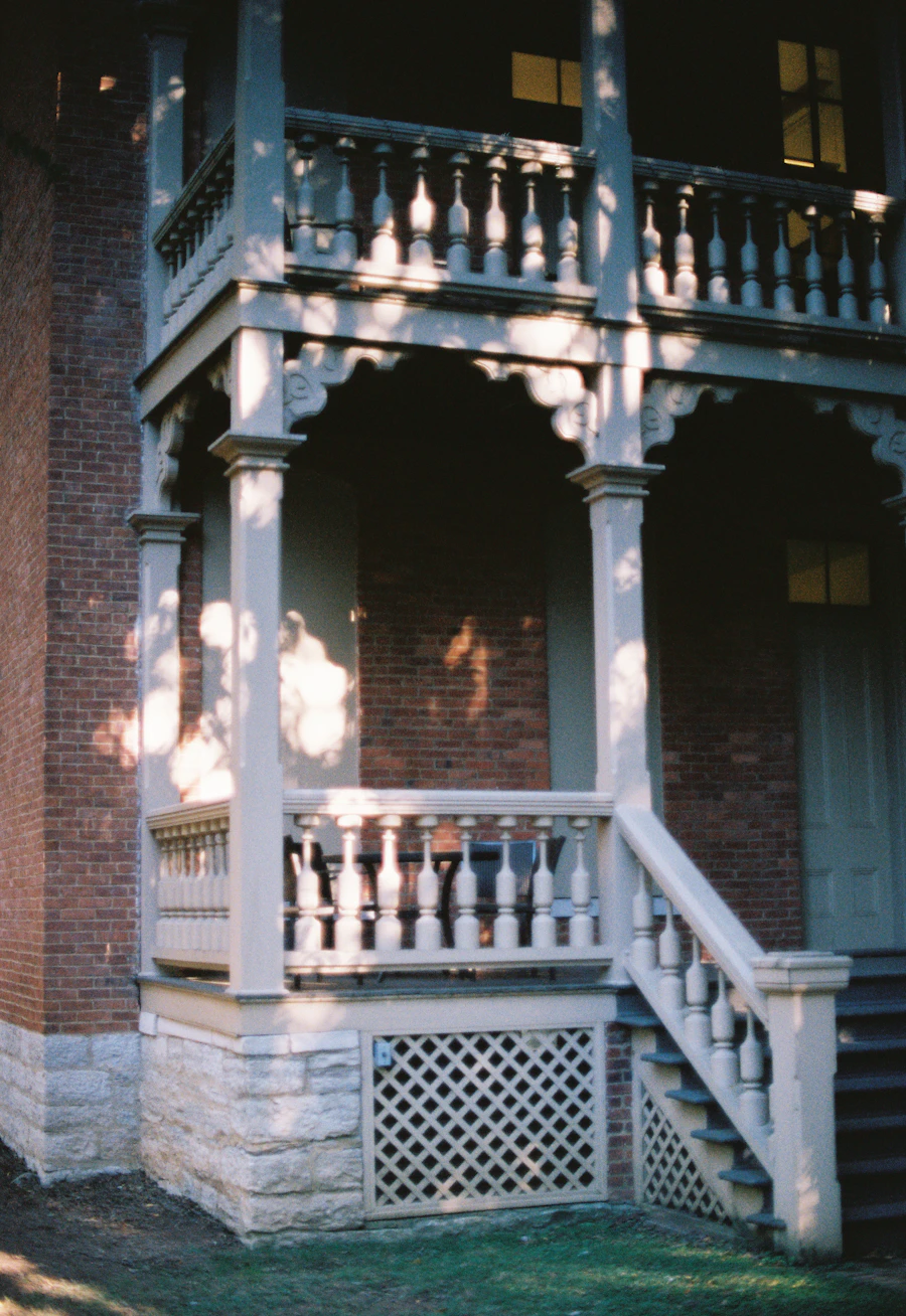 A white porch with turned spindles on a brick house