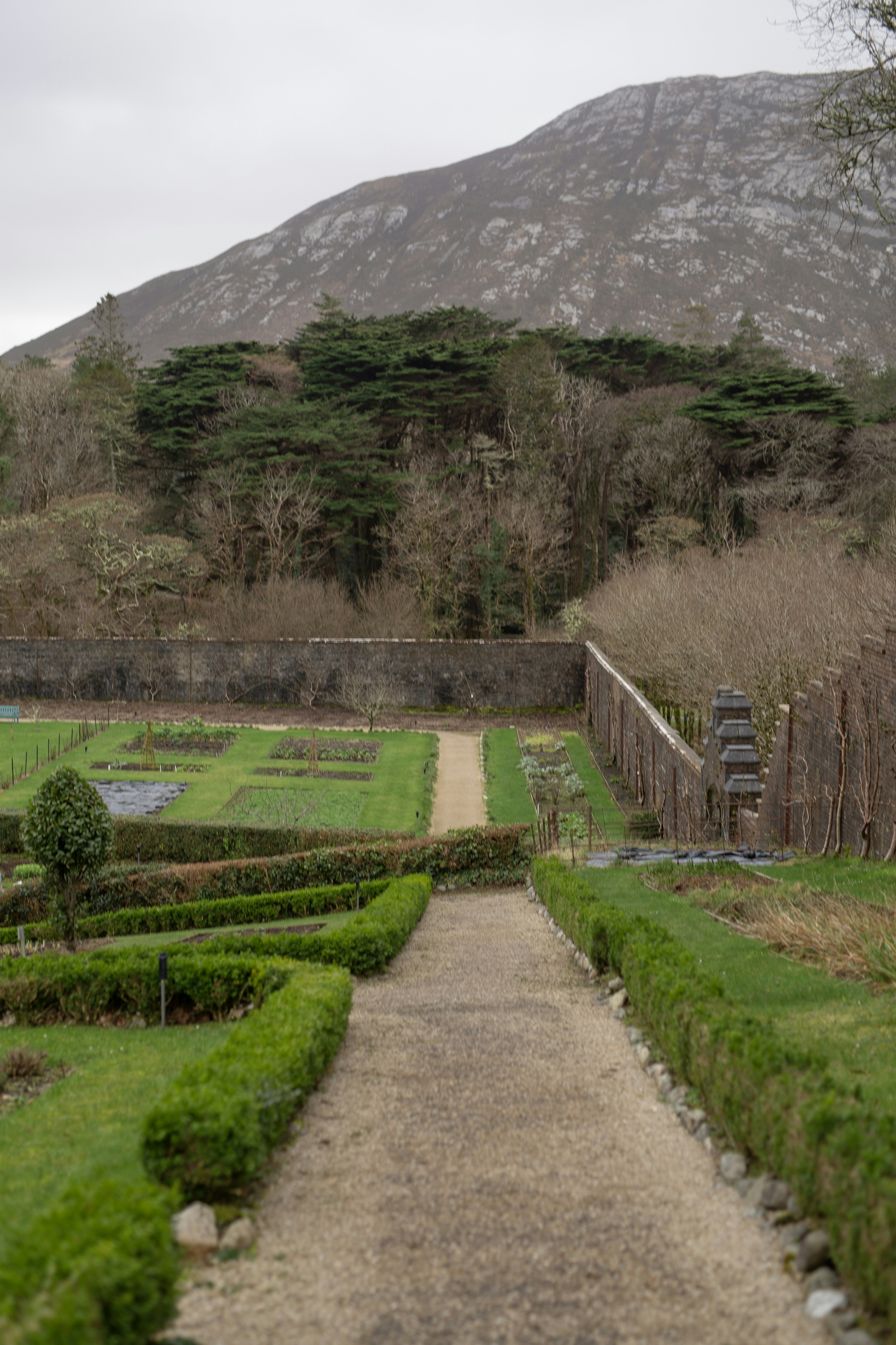 Un sendero formal de jardín conduce hacia un telón de fondo montañoso.