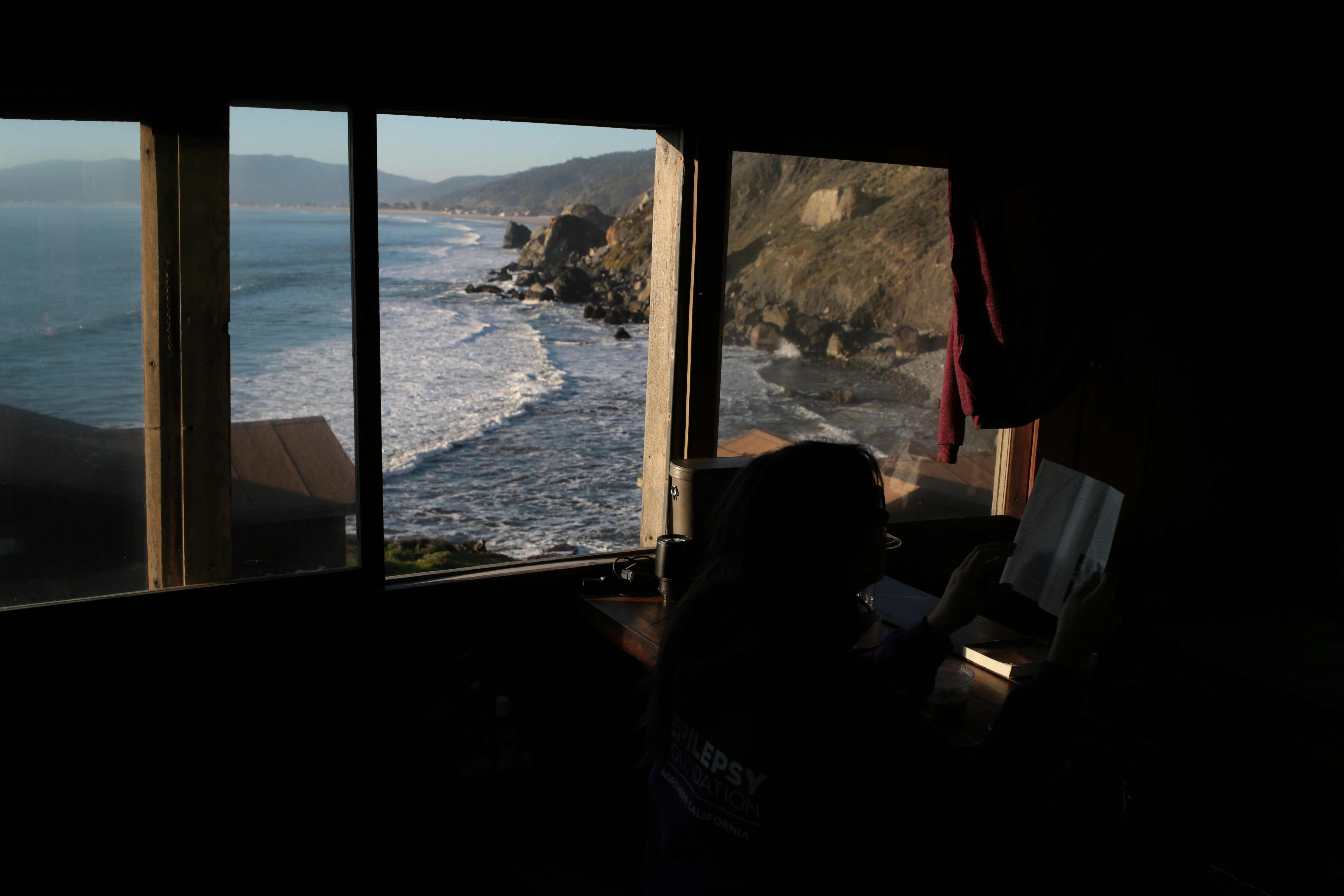 Ocean waves crash on a rocky coastline viewed from window.