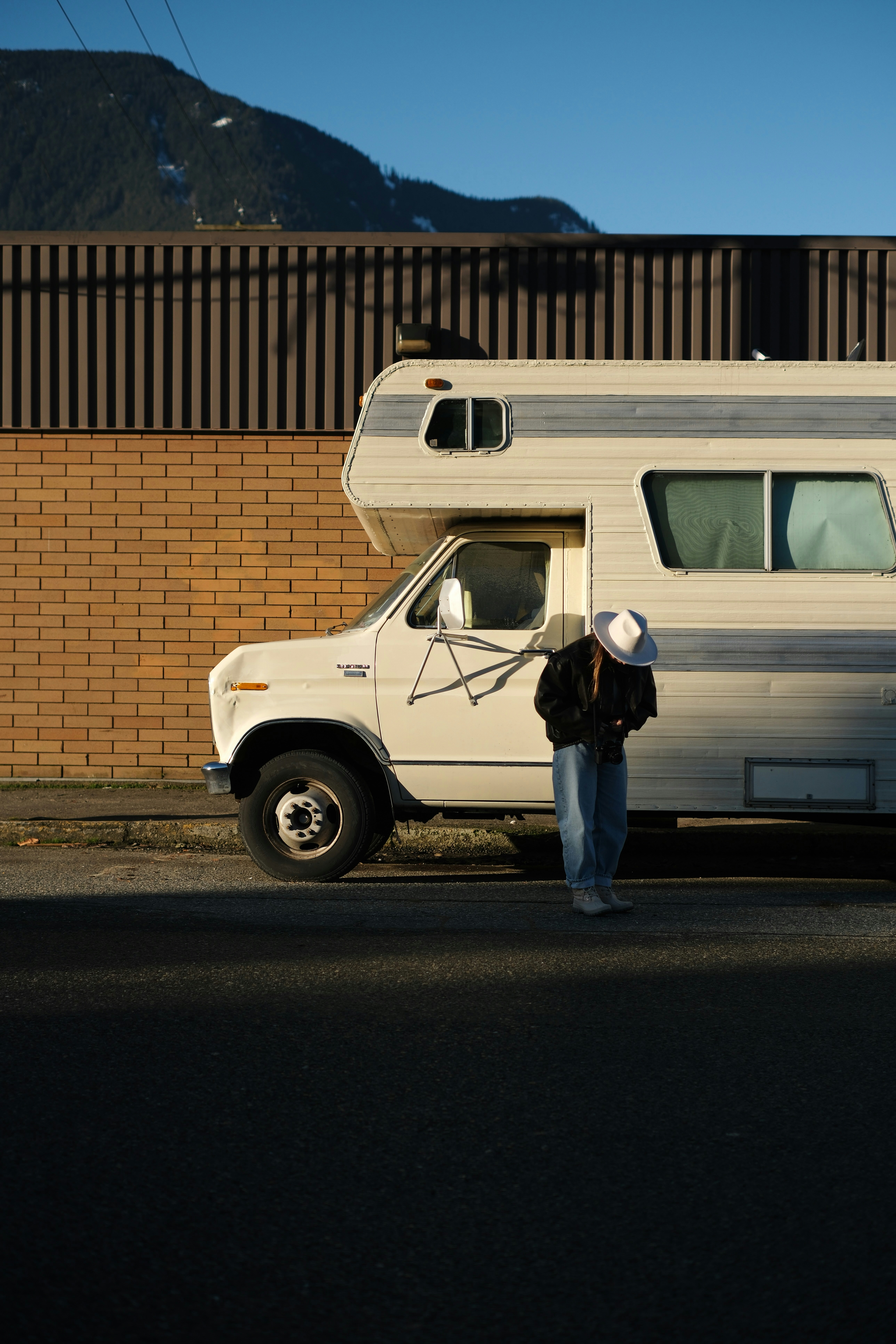 Person in hat stands by a camper van.