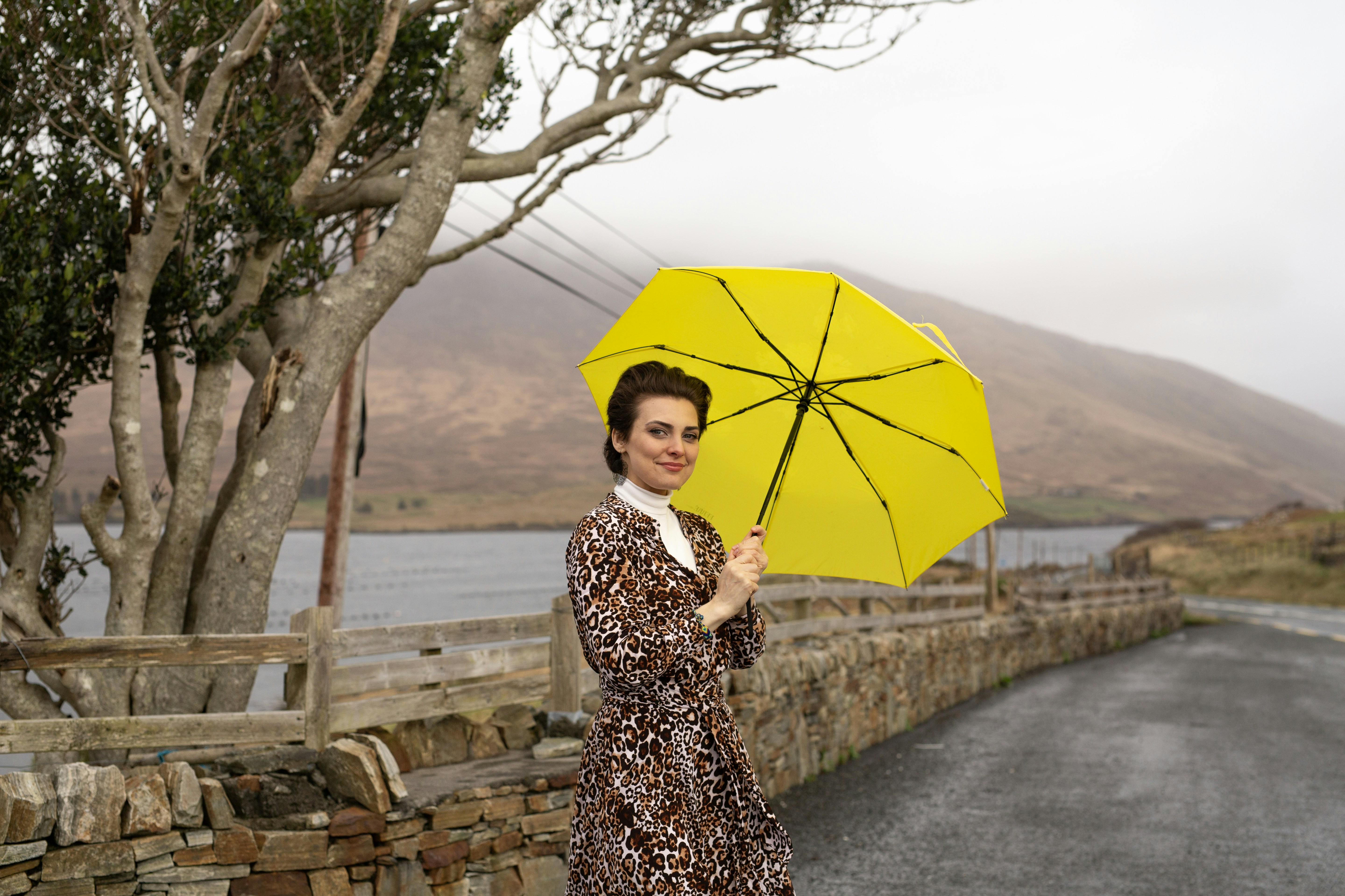 Woman holding yellow umbrella on a rainy day