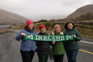 Four women hold an ireland scarf outdoors.