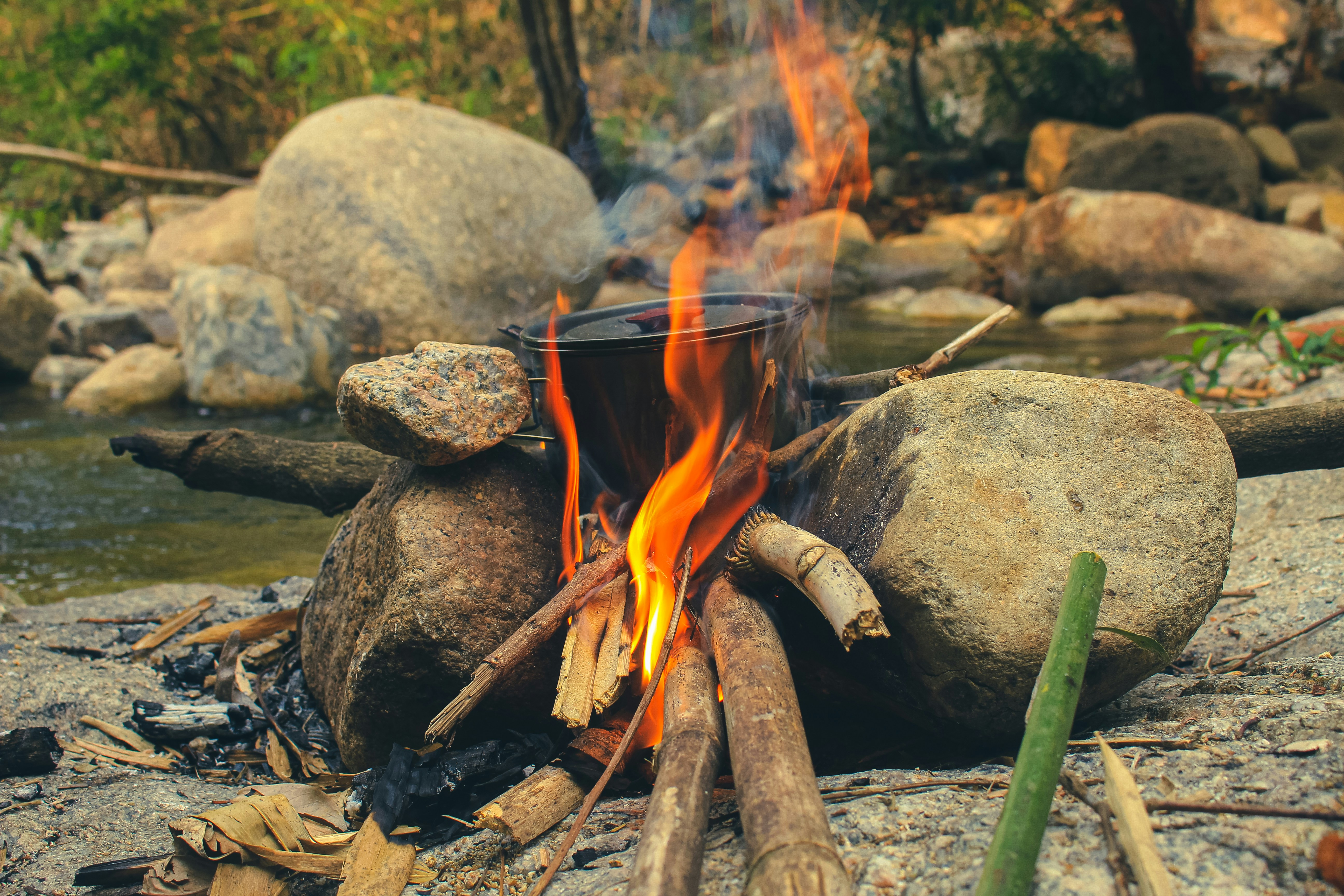 Lagerfeuerkochen mit Topf über Flammen