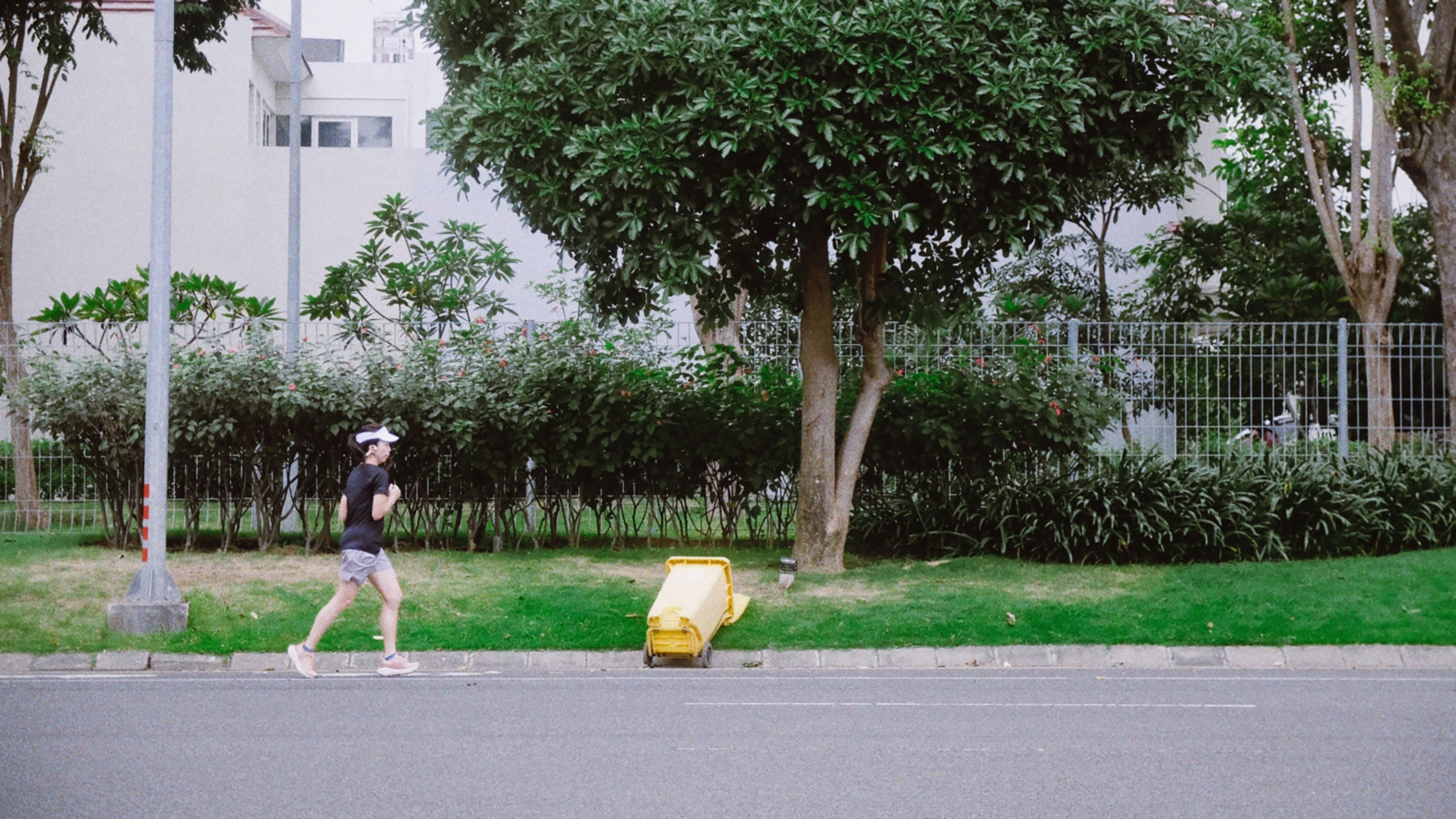 Una mujer trota junto a un robot amarillo de reparto en la acera.