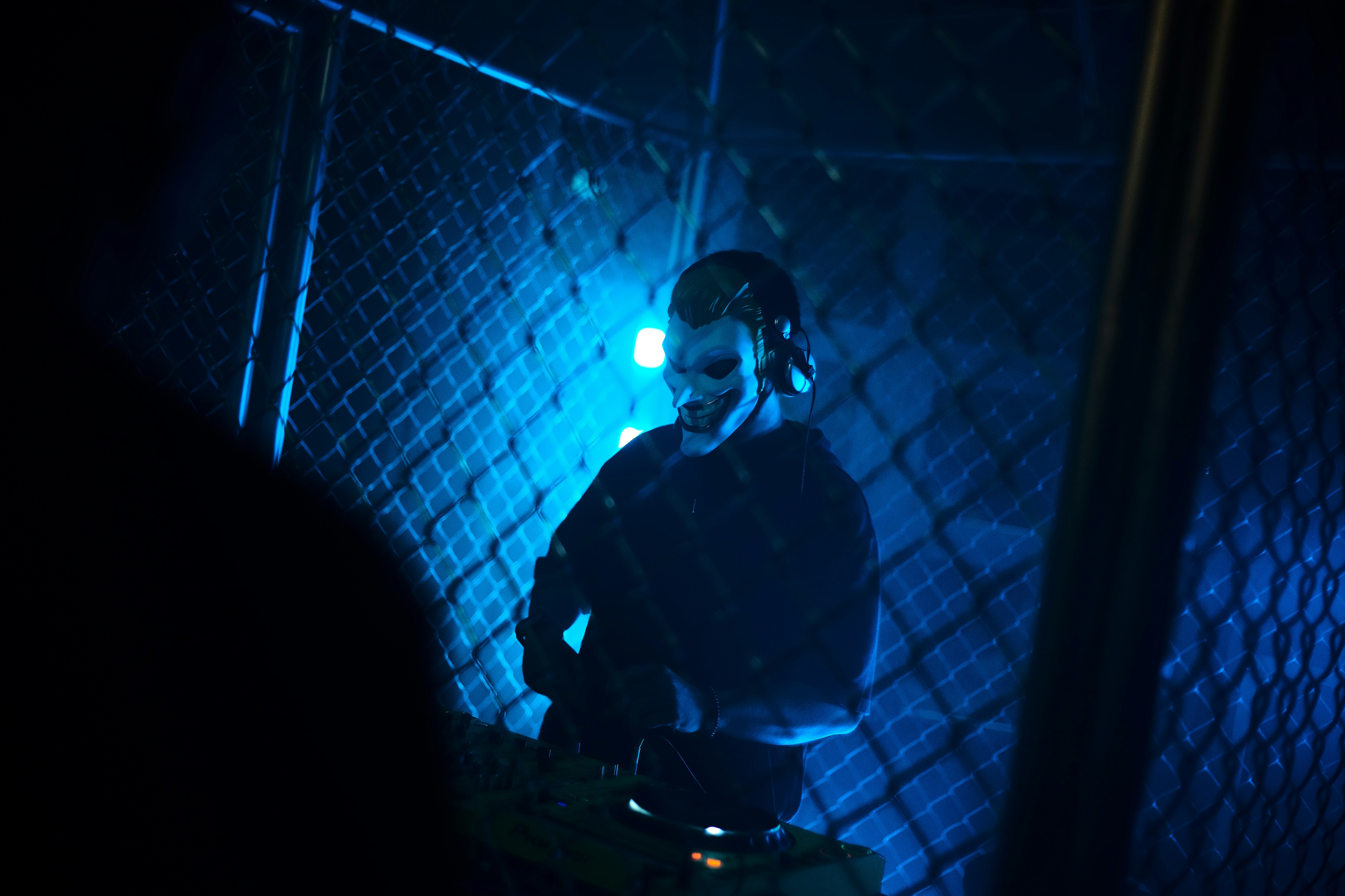 Dj performing with blue lights behind fence
