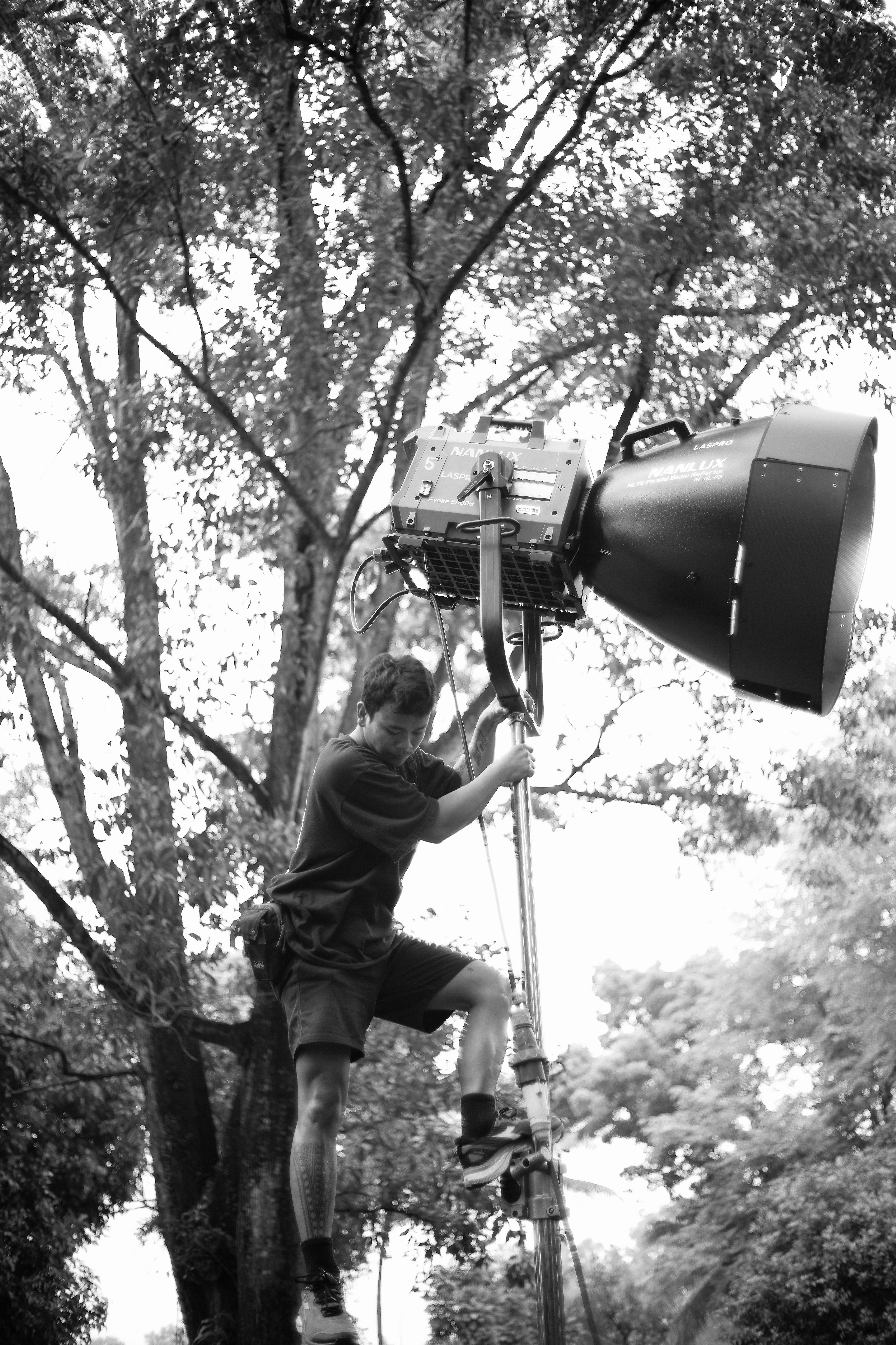Homme ajustant un grand projecteur sur un grand poteau