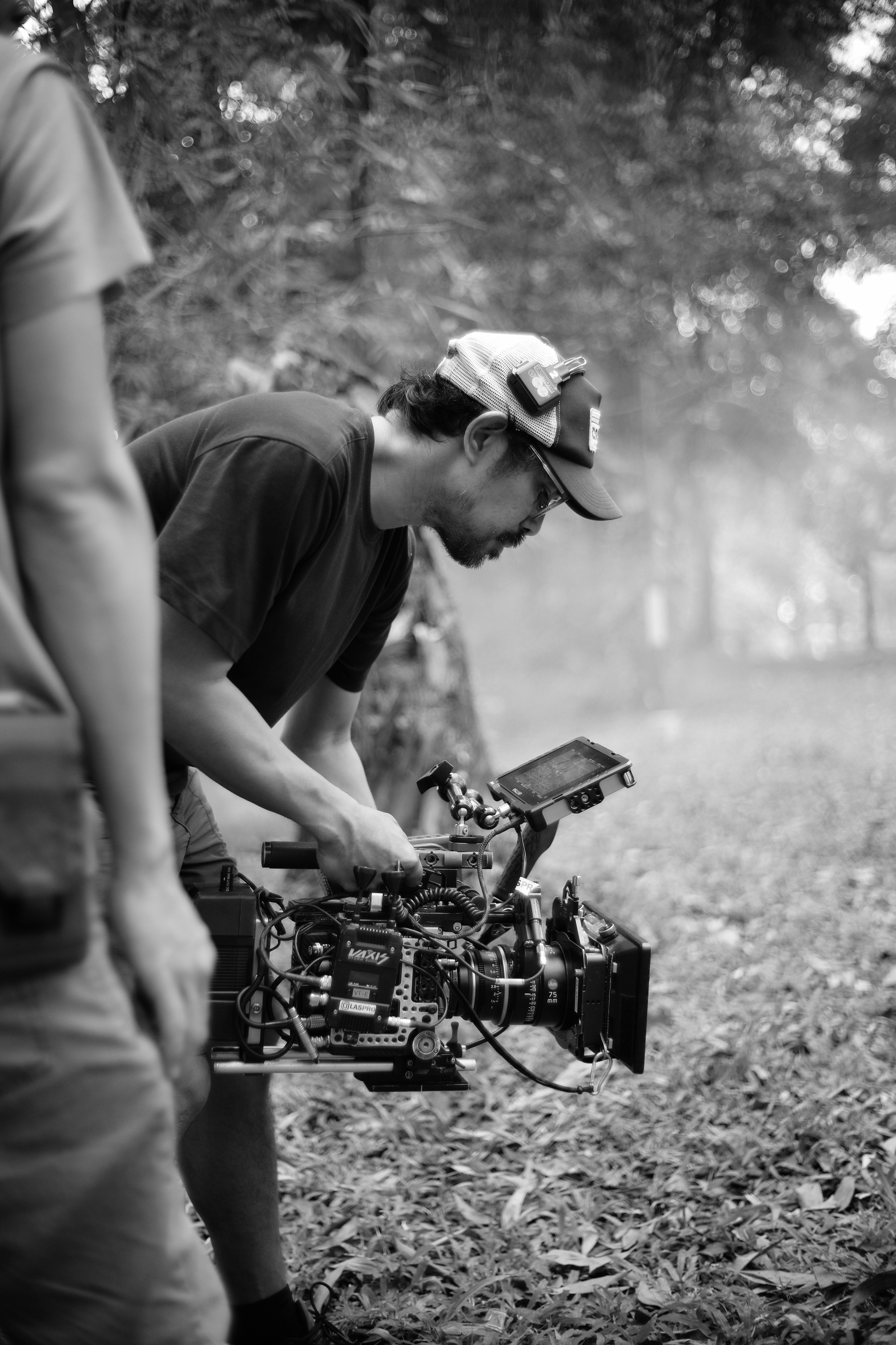 Filmmaker operating a professional video camera outdoors.