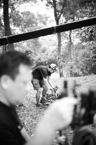 Man adjusting camera equipment in a forest setting