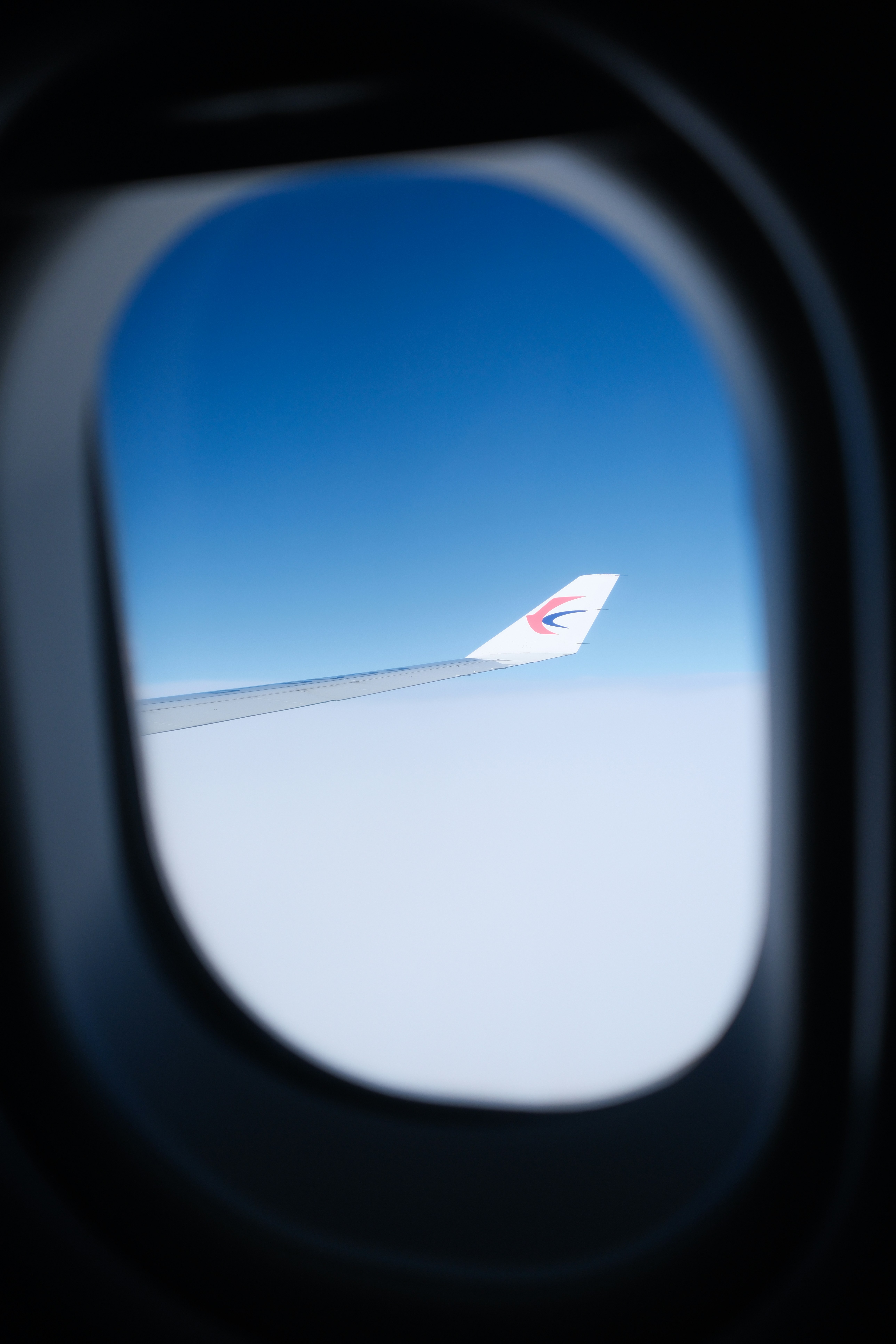 Airplane wing seen through a window above clouds