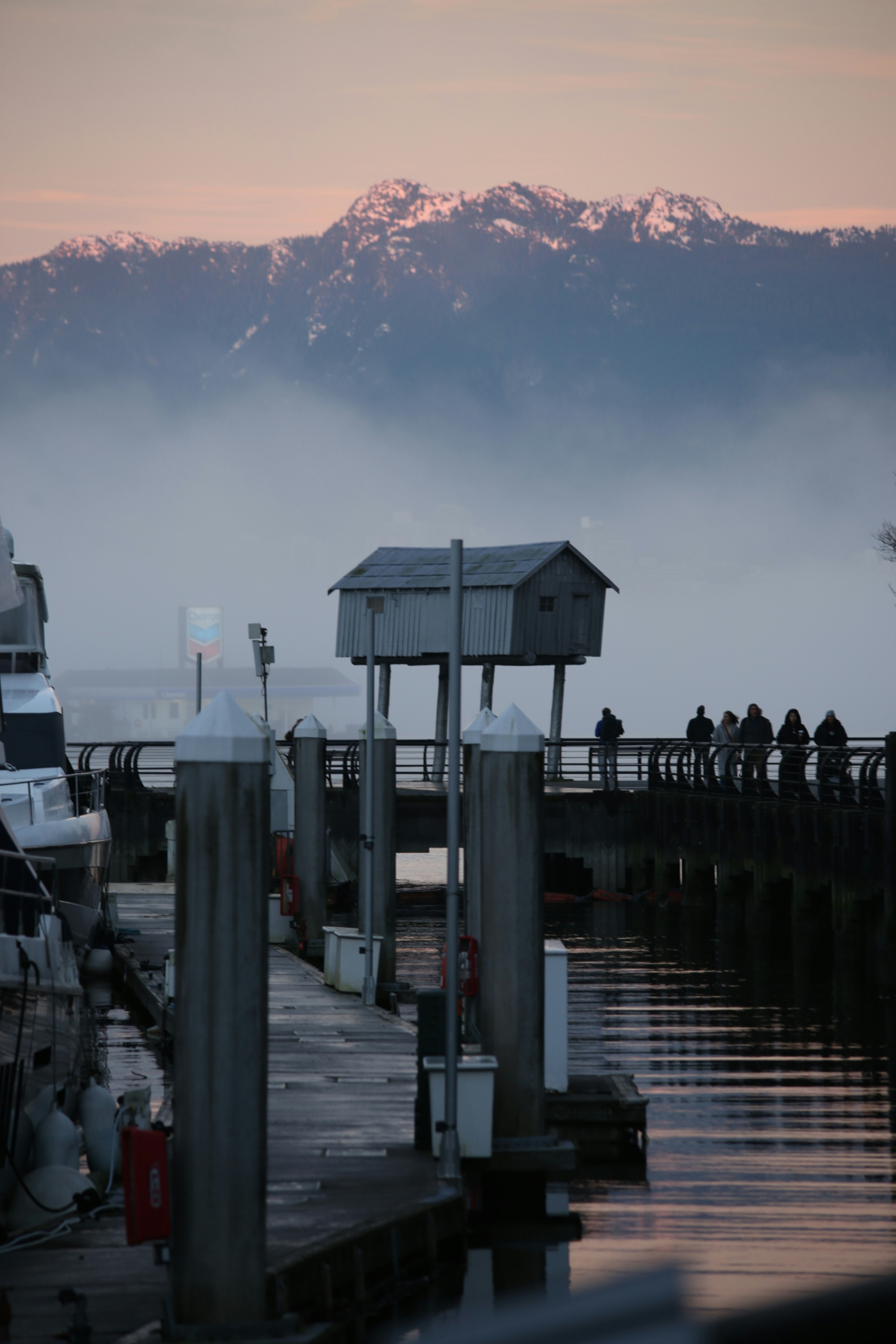 A small shack on stilts over a pier with mountains.