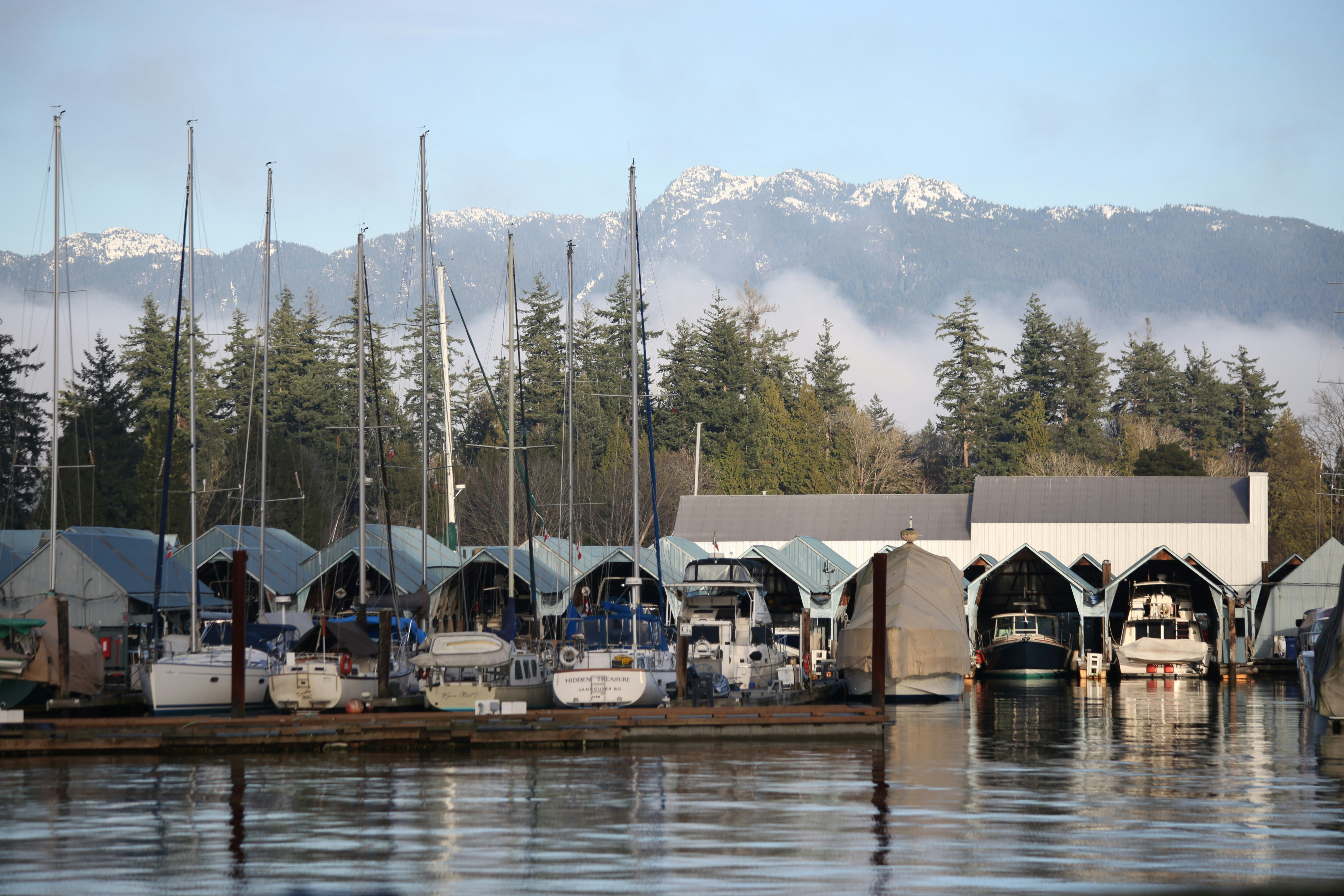 Sailboats docked at a marina with mountains in background
