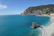 Turquoise ocean meets a sandy beach with a cliffside town.