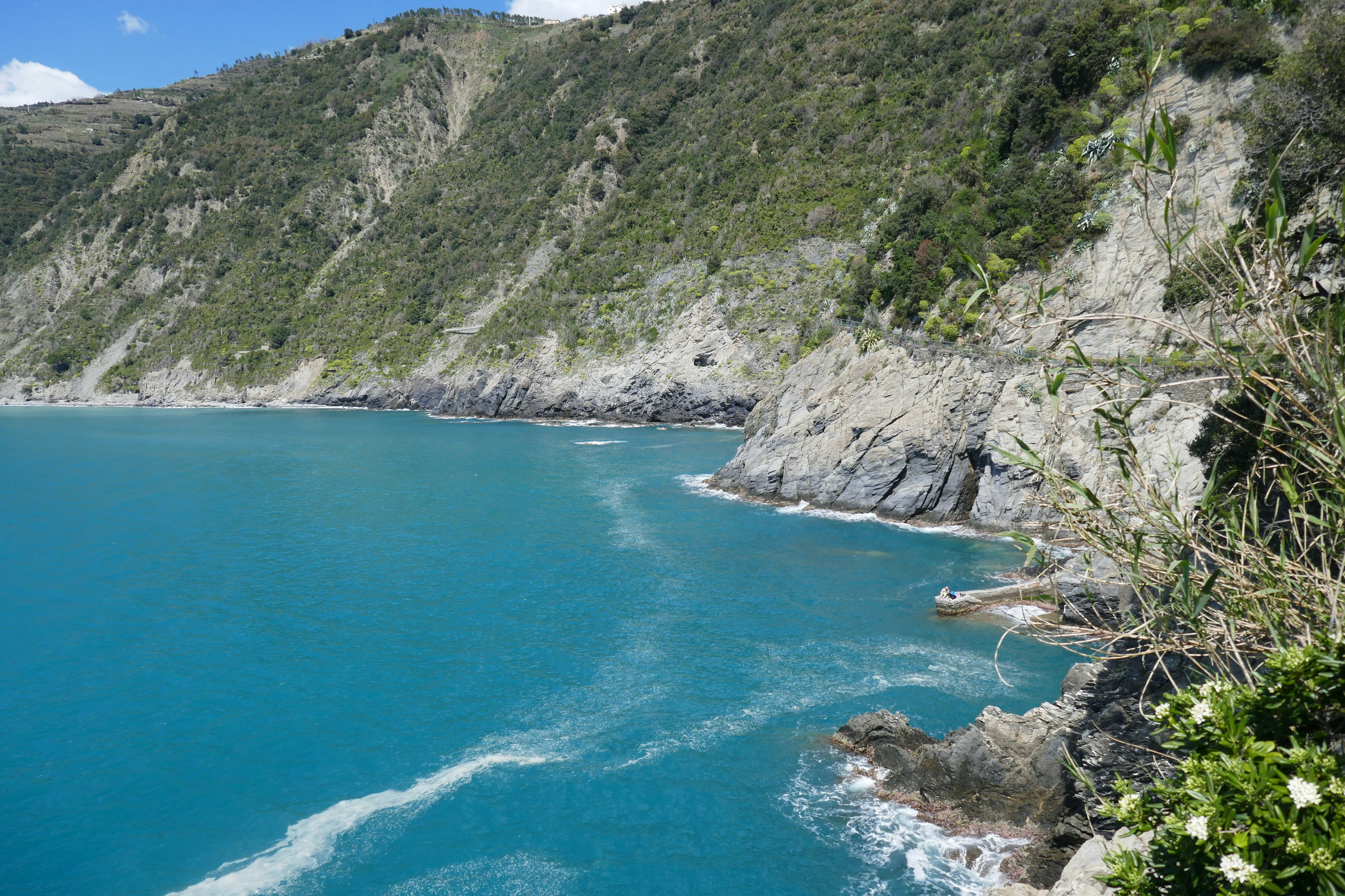Turquoise ocean water meets rocky coastline under a blue sky.
