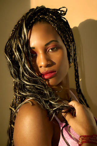 Woman with braided hair and bold makeup poses.