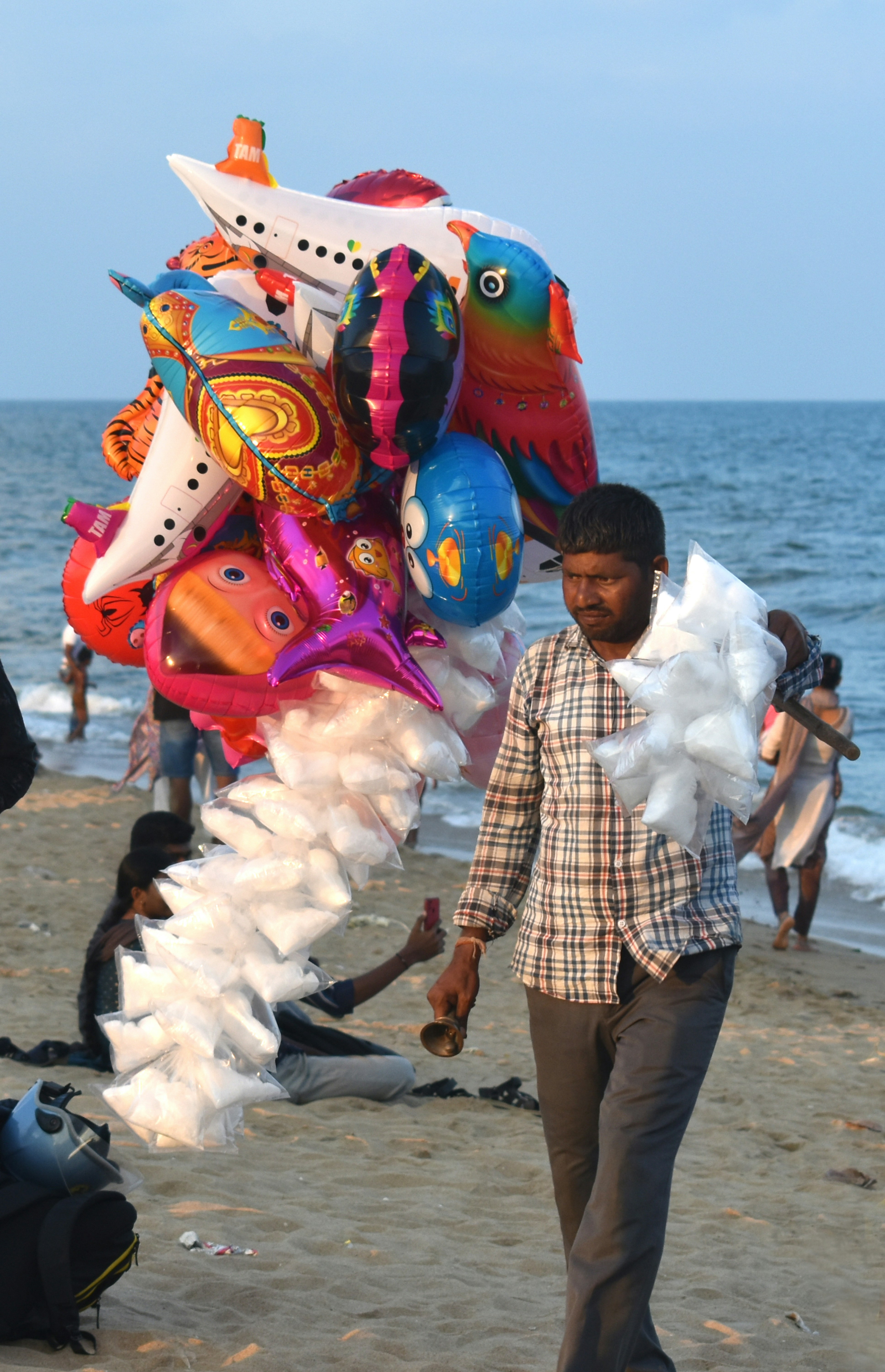 Man selling balloons on a beach near the ocean