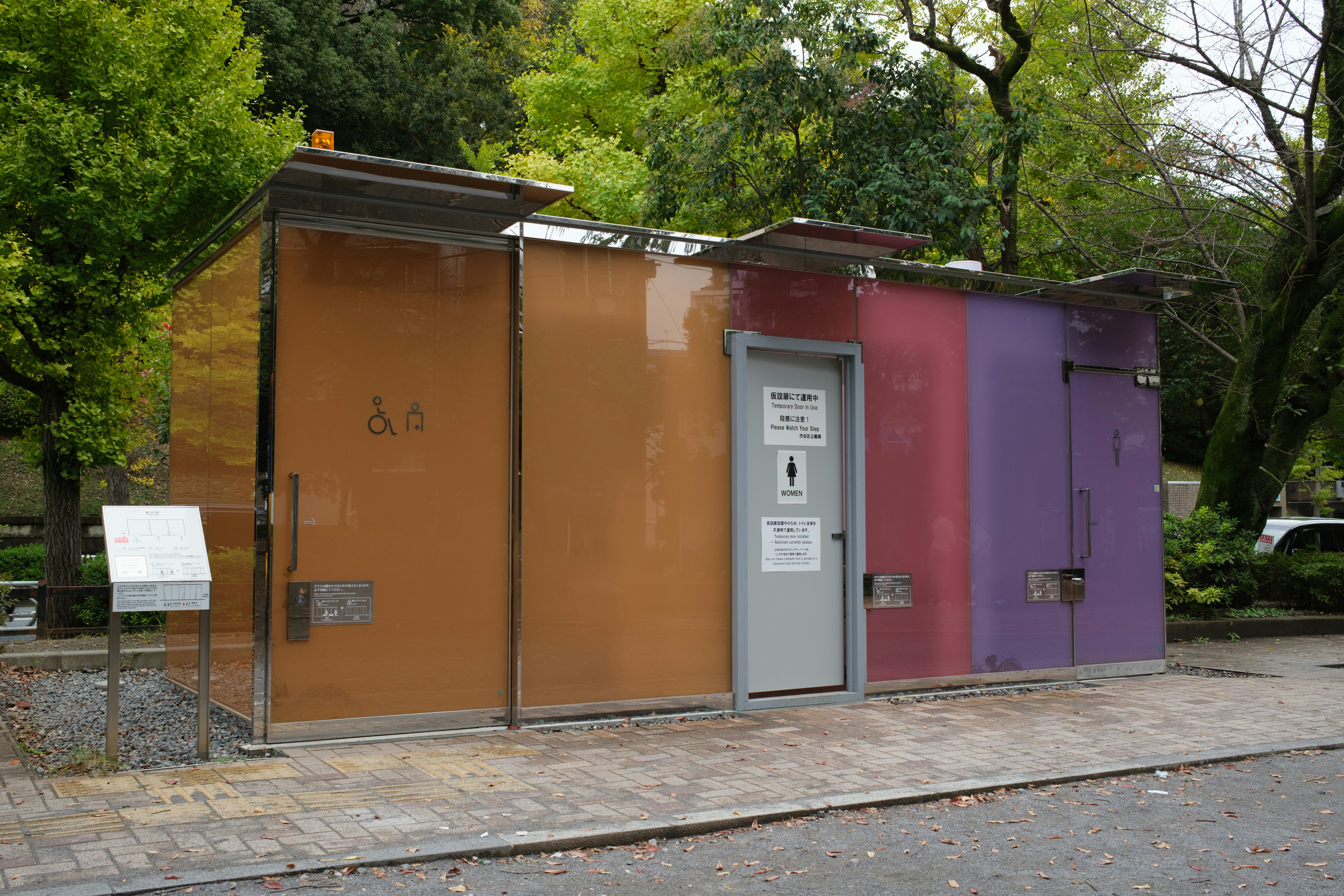 Buntes öffentliches Toilettengebäude mit Bäumen im Hintergrund
