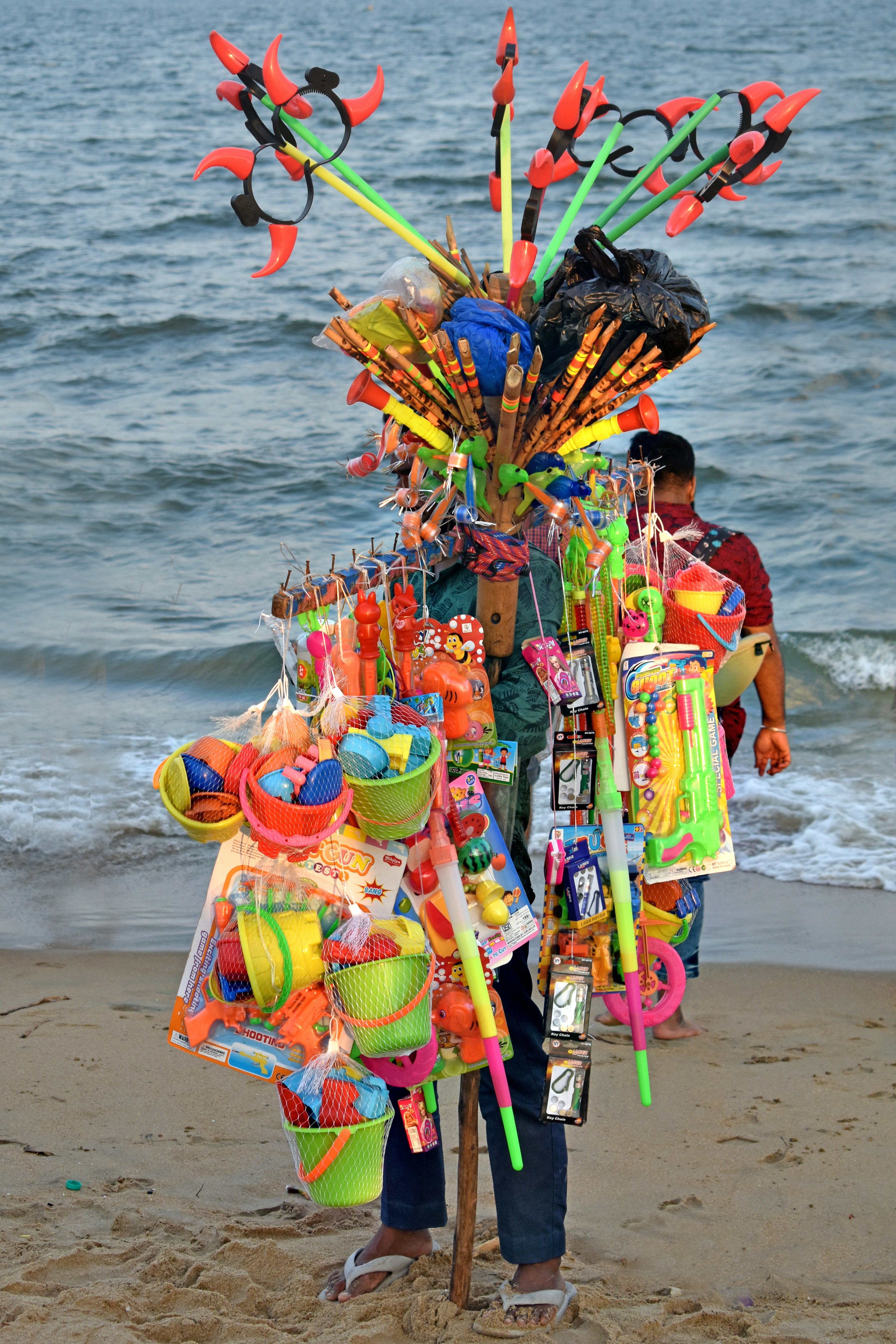 Händler mit bunten Spielzeugen an einem Sandstrand