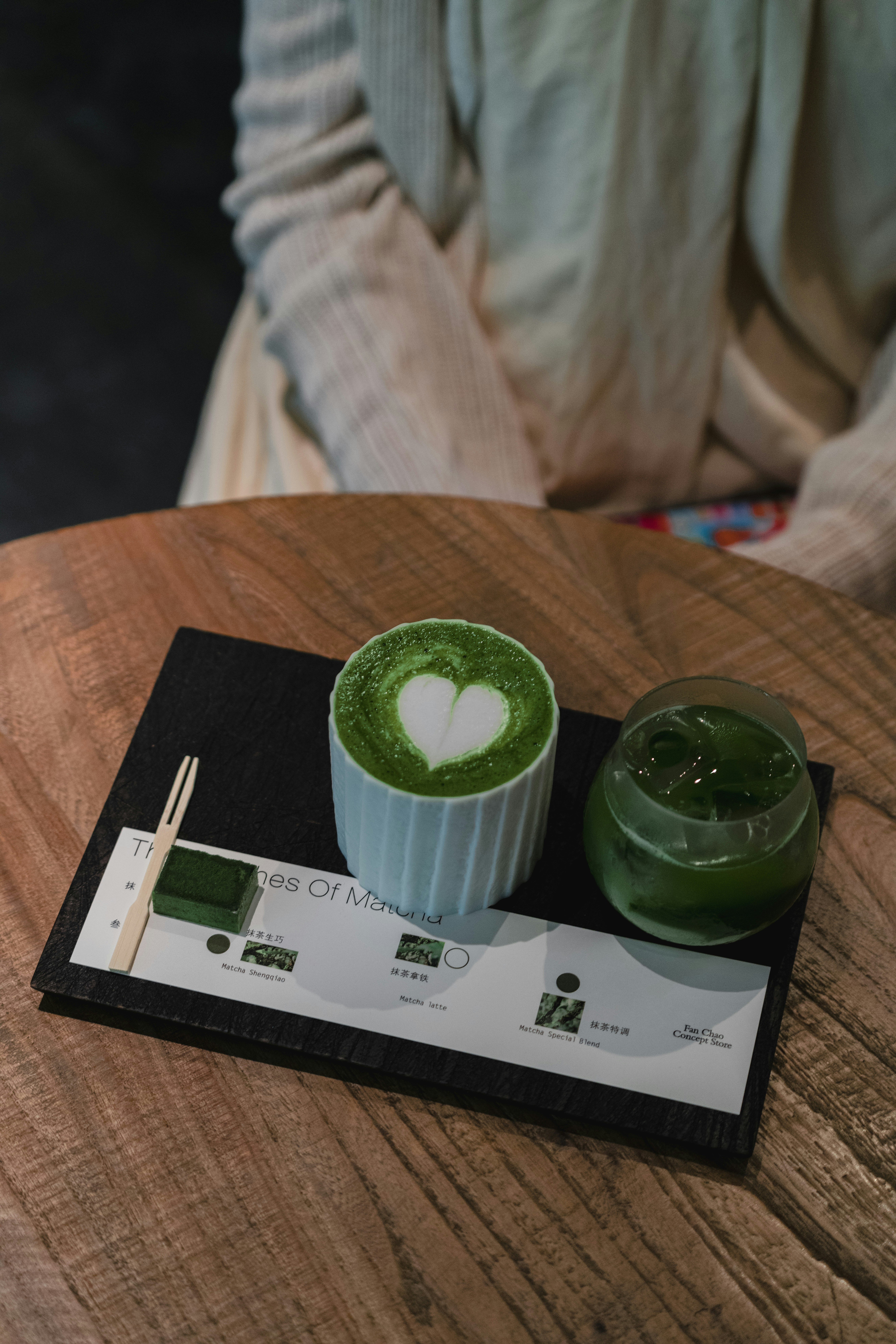Two matcha drinks with heart art on a table.