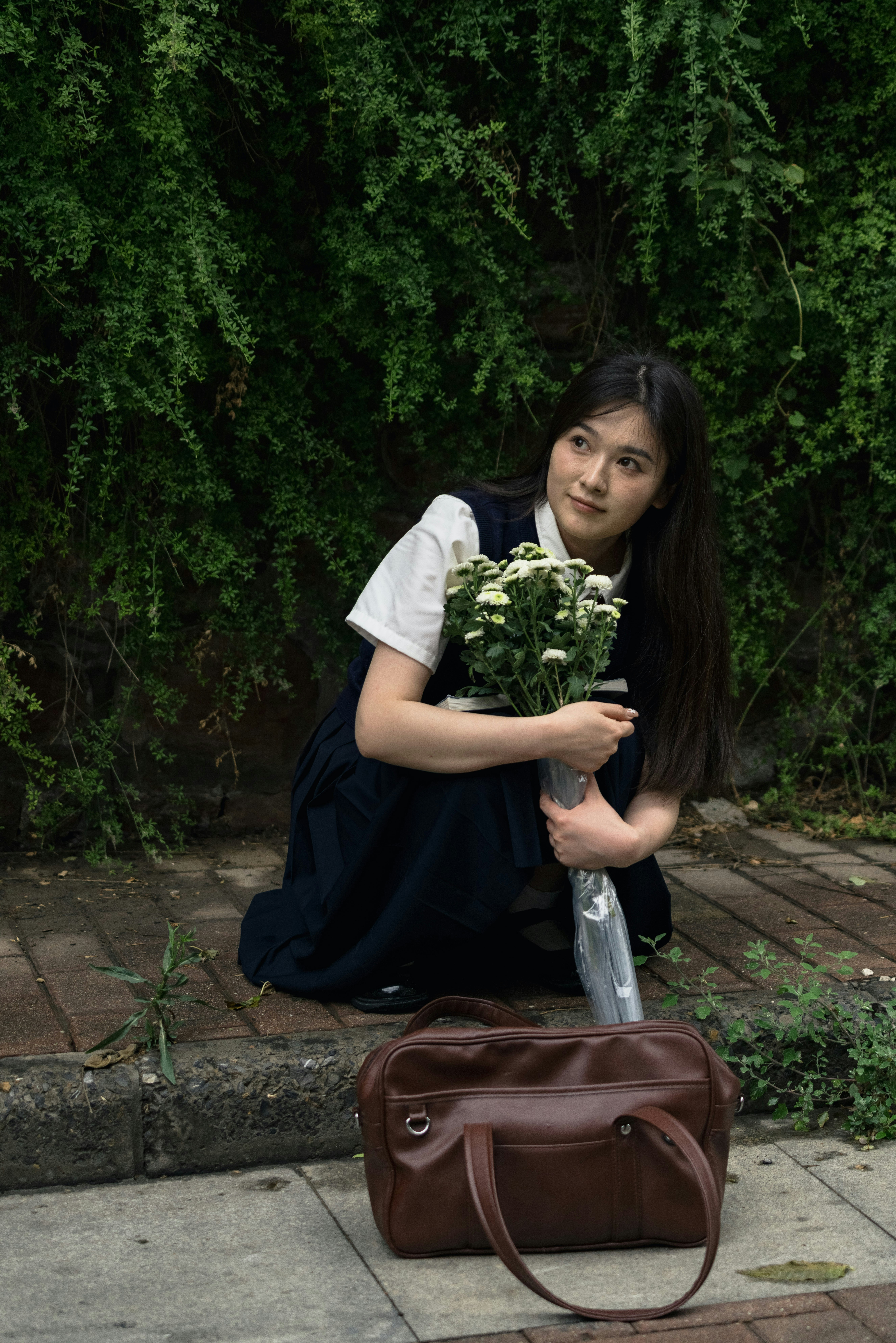 Young woman in school uniform holding flowers