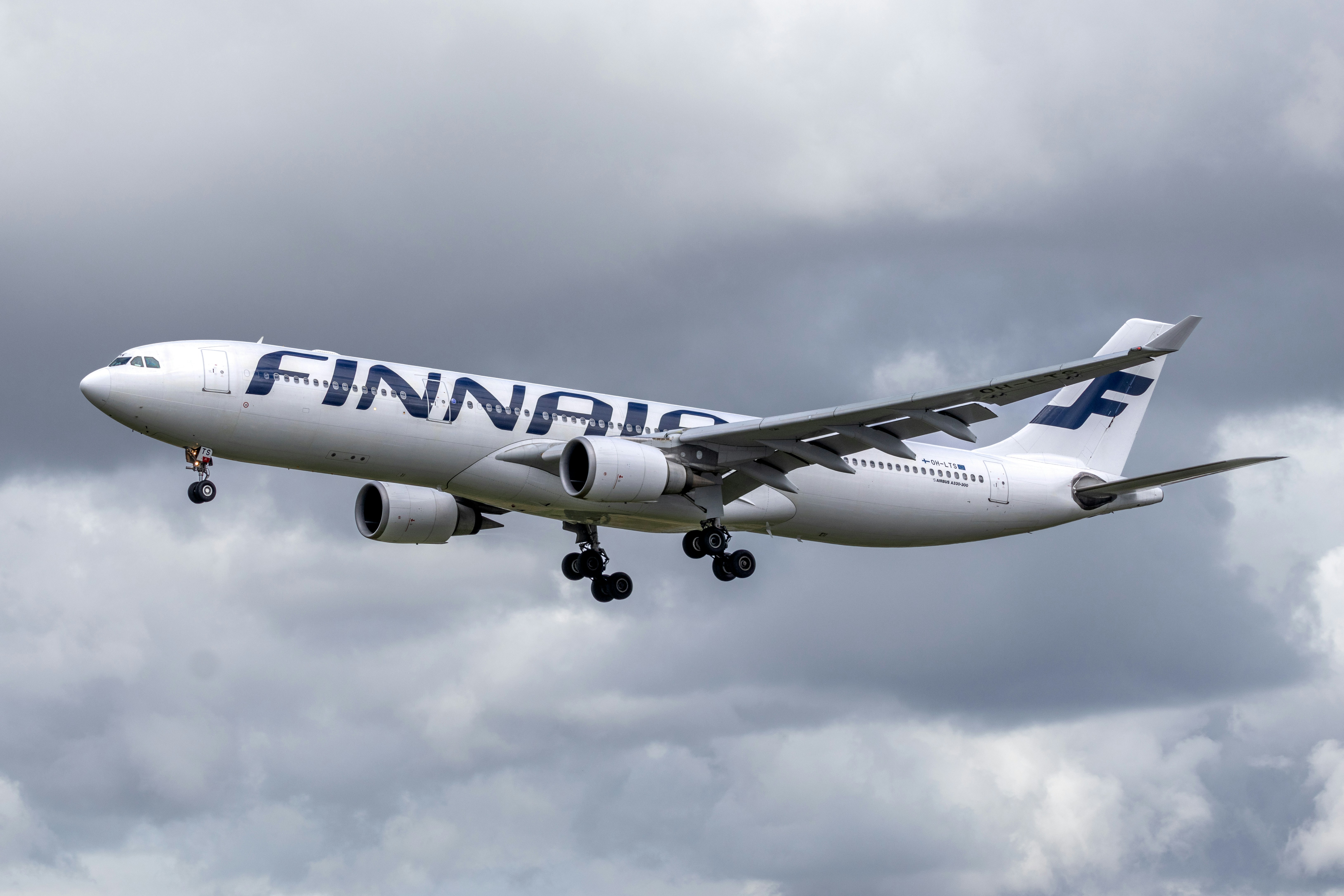 Finnair airplane flying under a cloudy sky