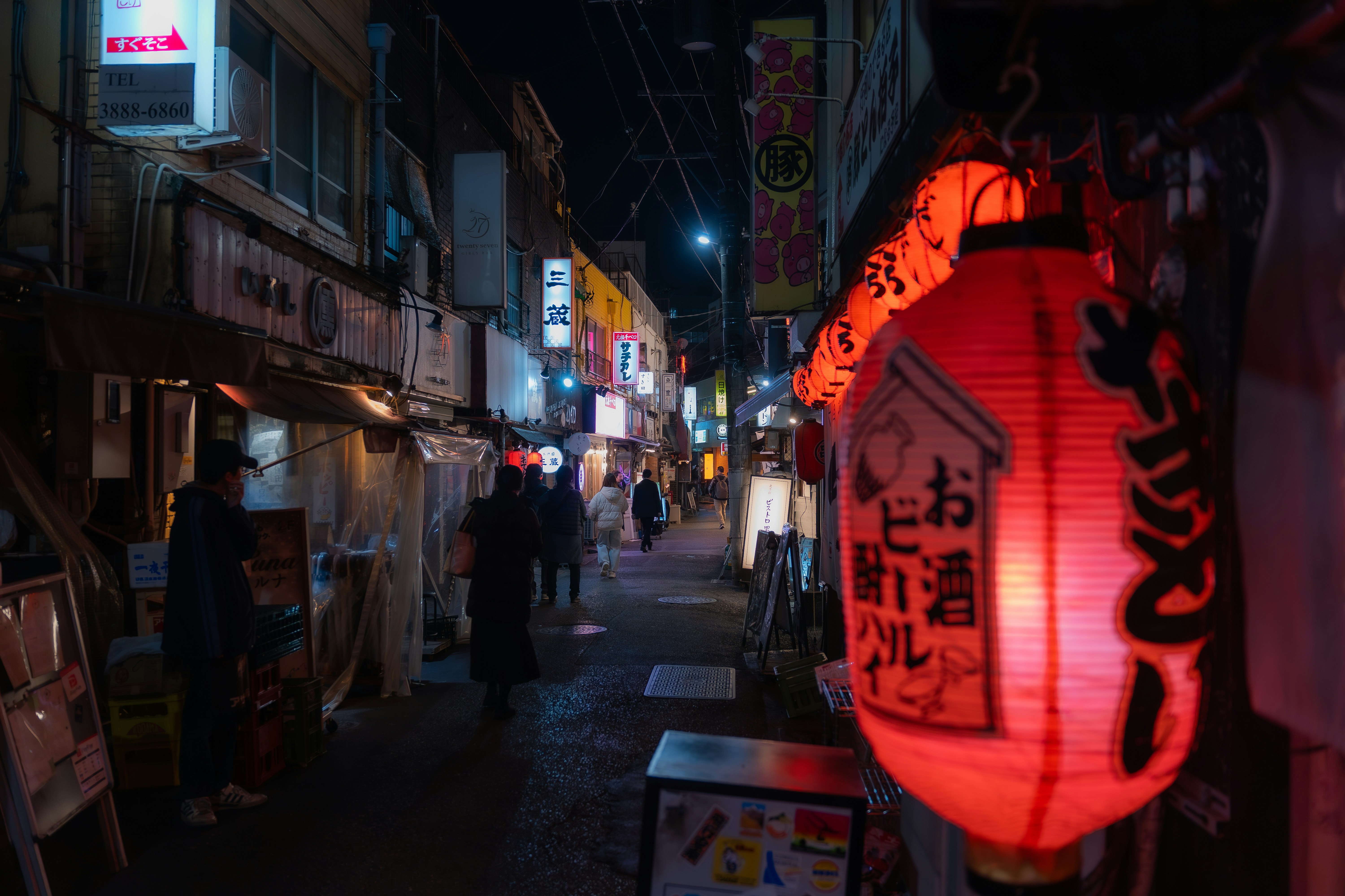 A narrow street at night with glowing lanterns.