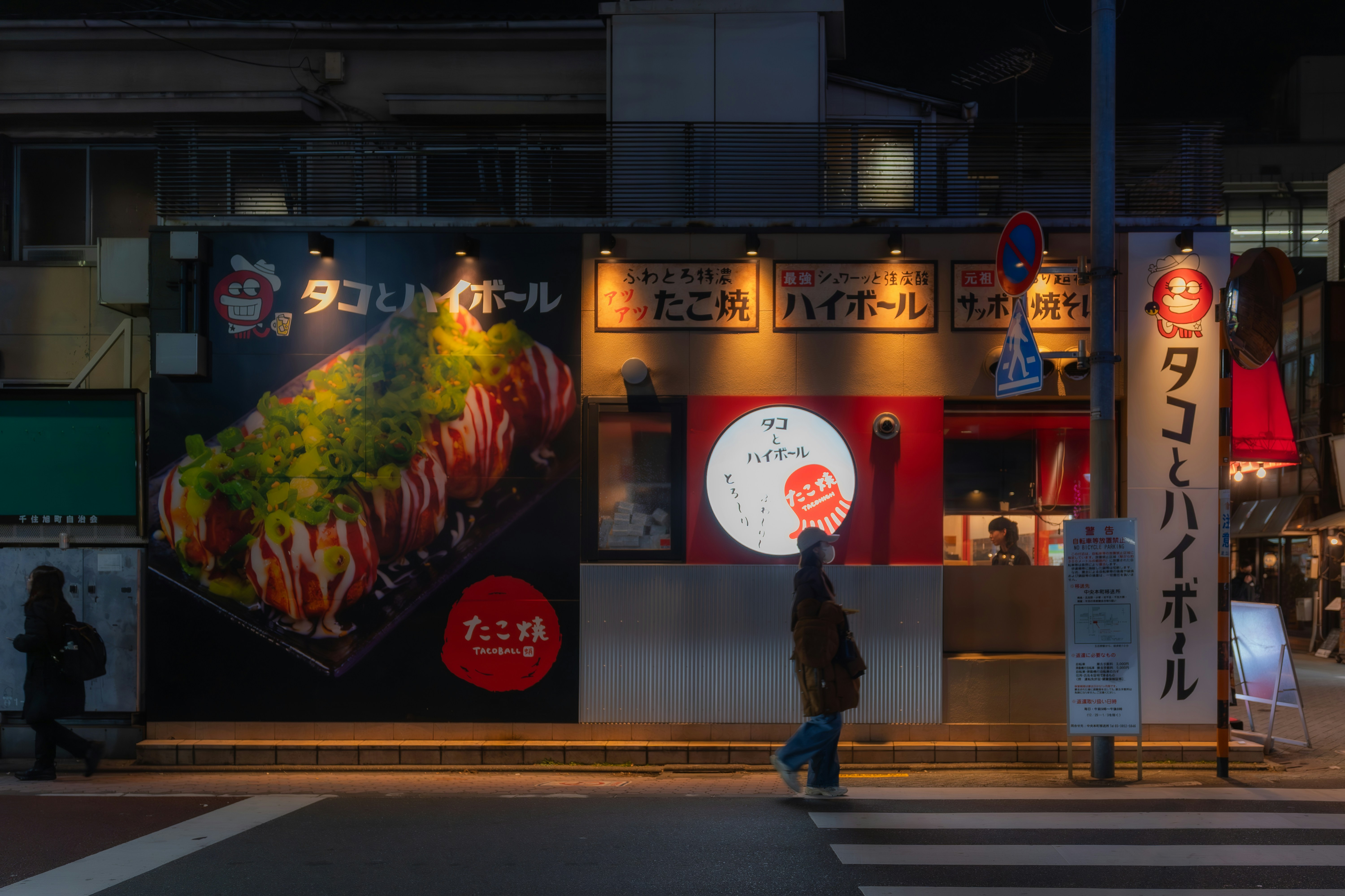 A brightly lit restaurant facade at night with food advertising.