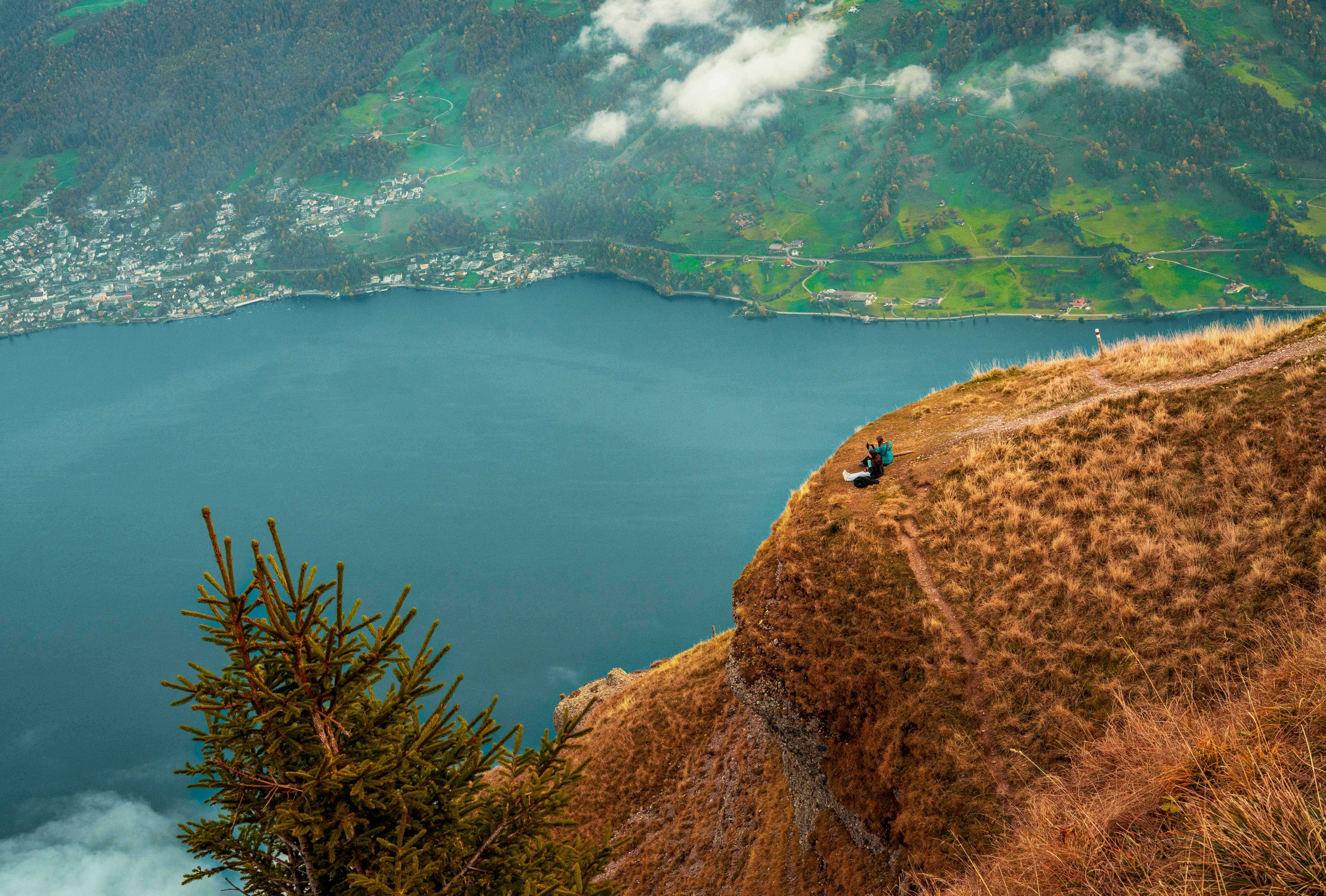 Person sits on a cliff overlooking a blue lake.