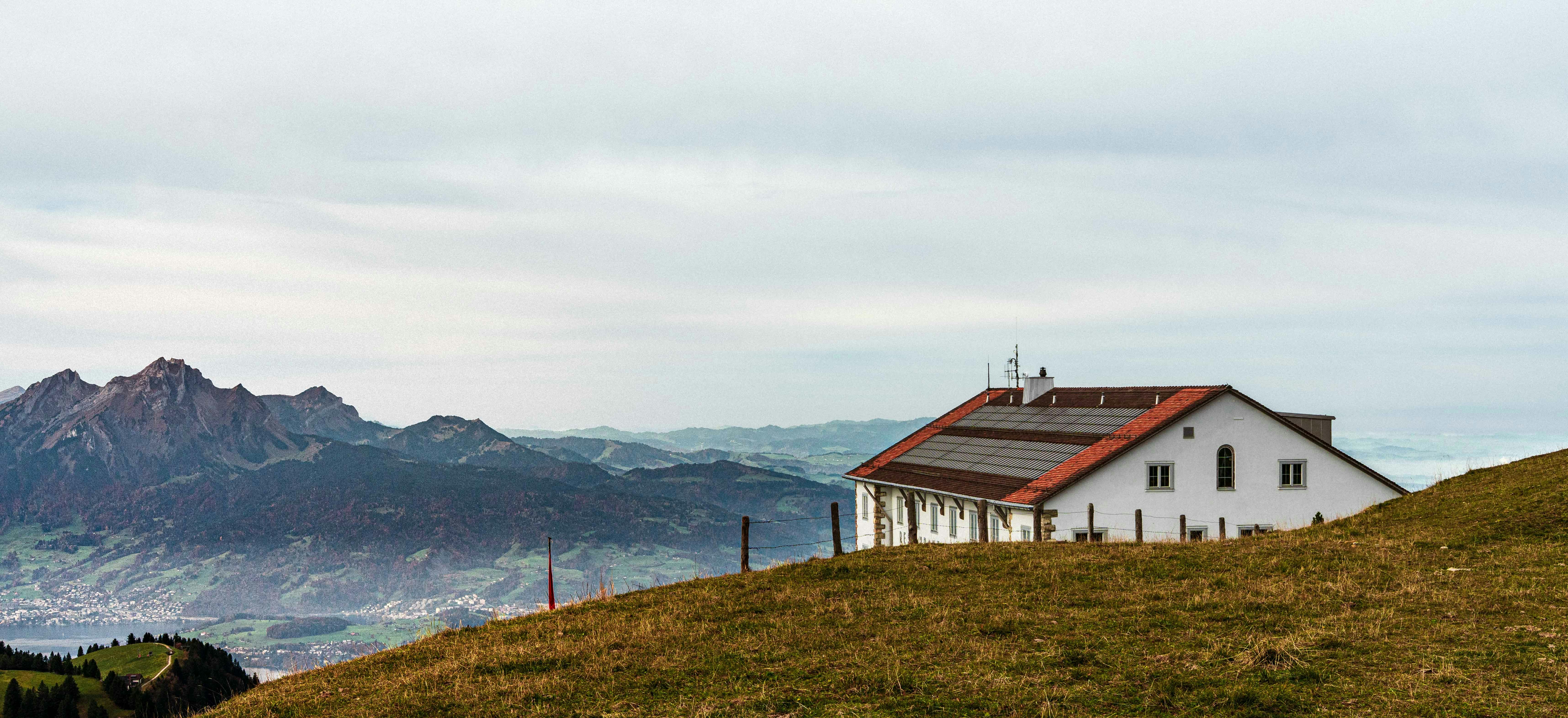 White building with solar panels on a grassy hill.