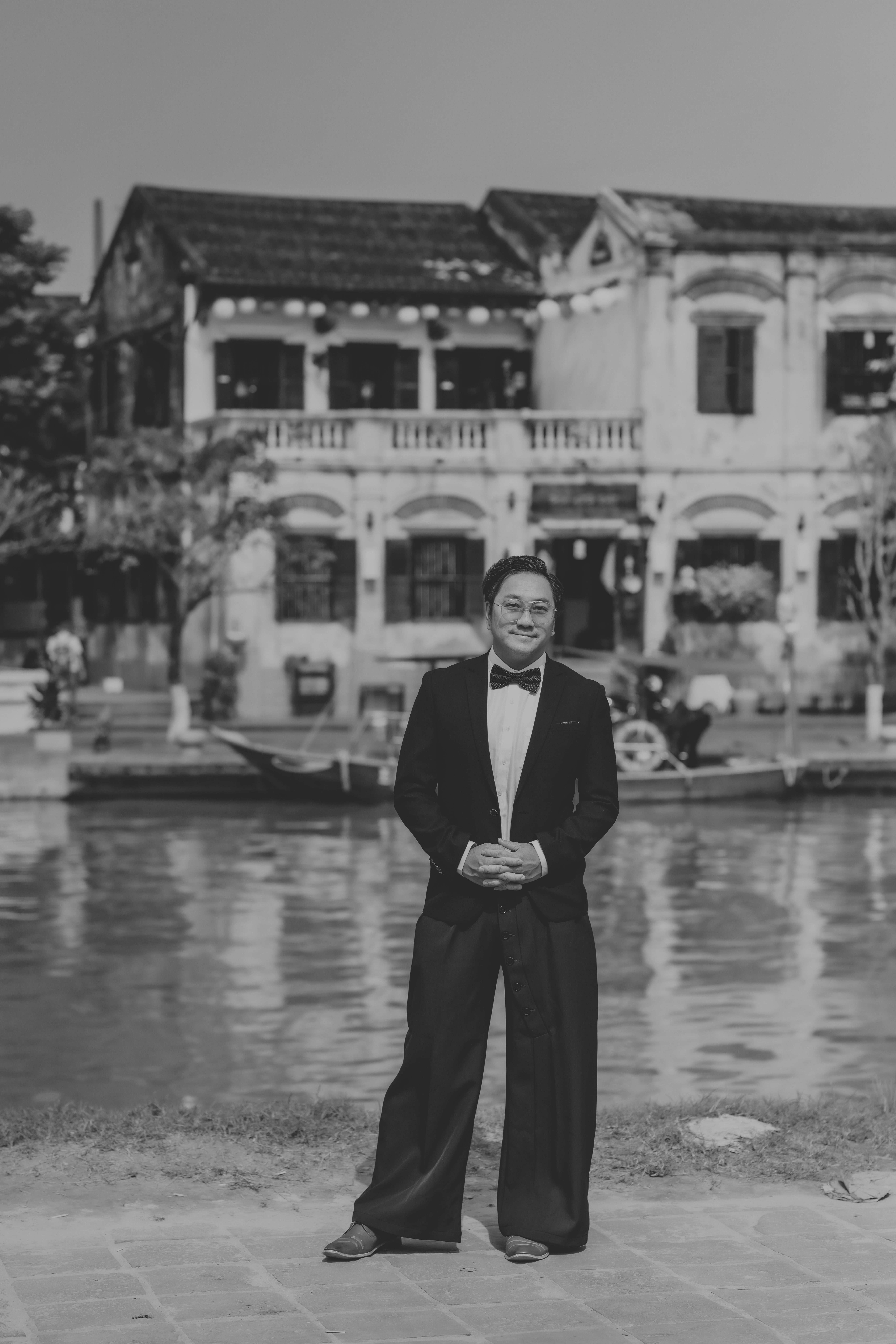 Man in a tuxedo standing by a canal