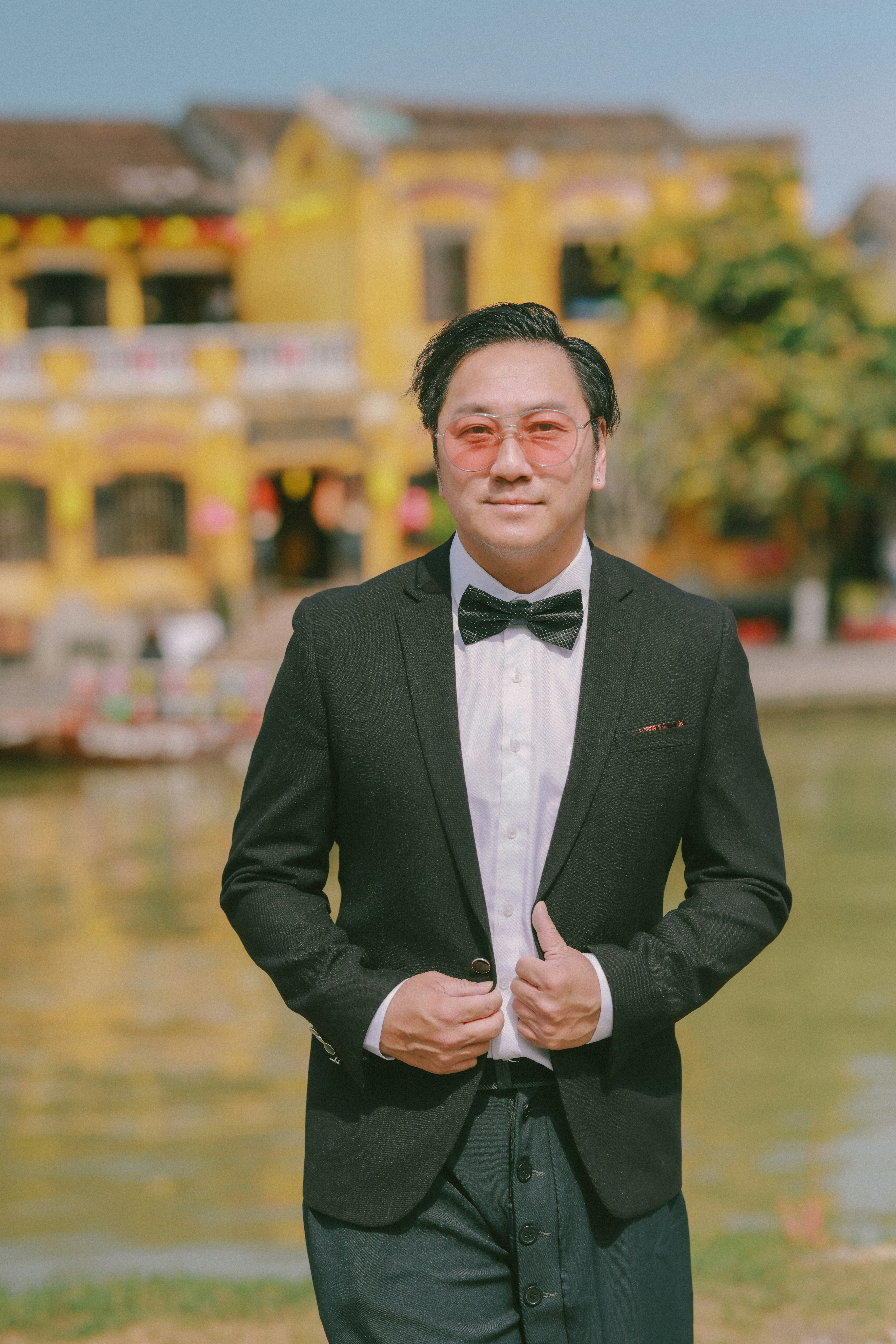 Hombre con traje y pajarita y gafas de sol rosas.