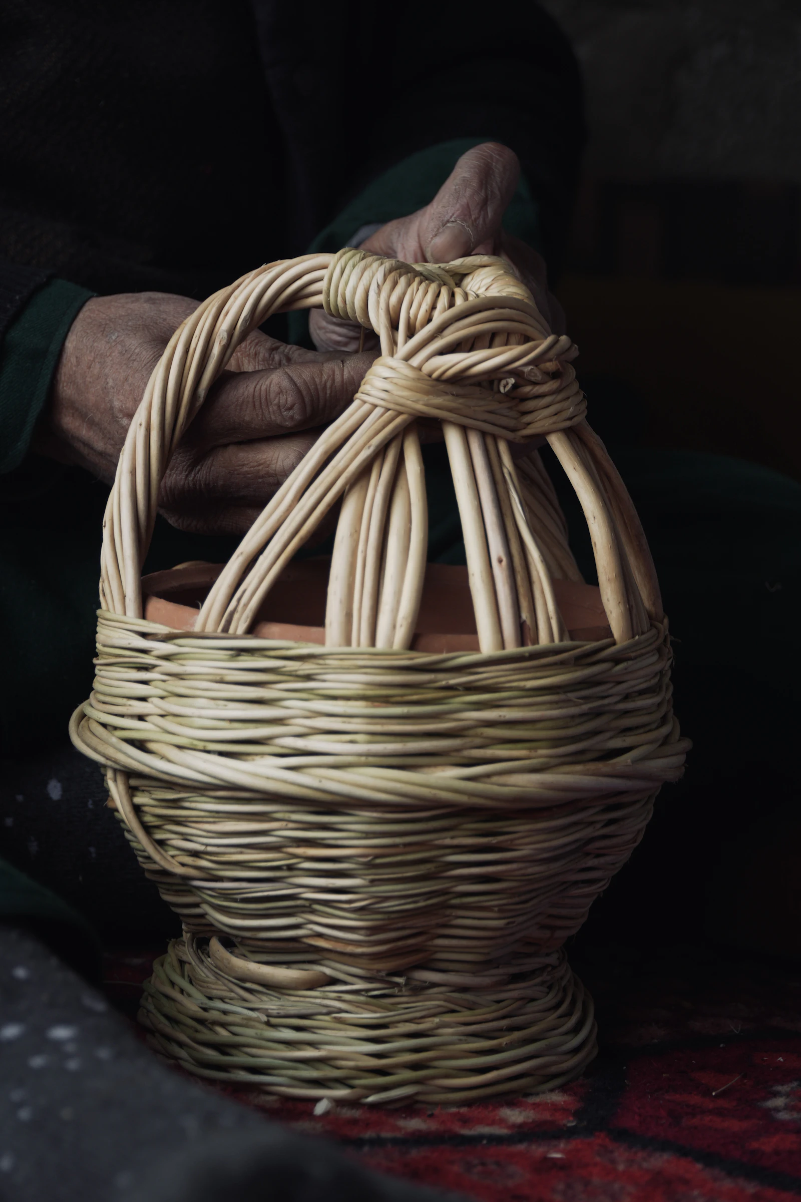 Hands weaving willow reed into a basket