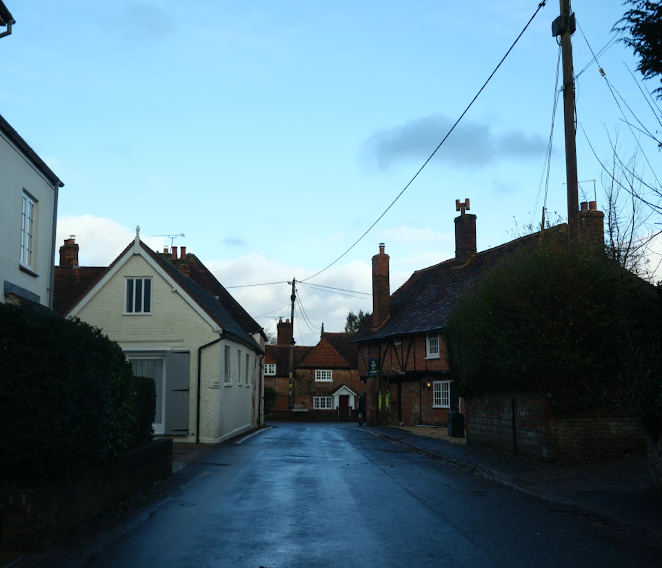 Two houses flank a narrow street with a person walking towards them in foreground