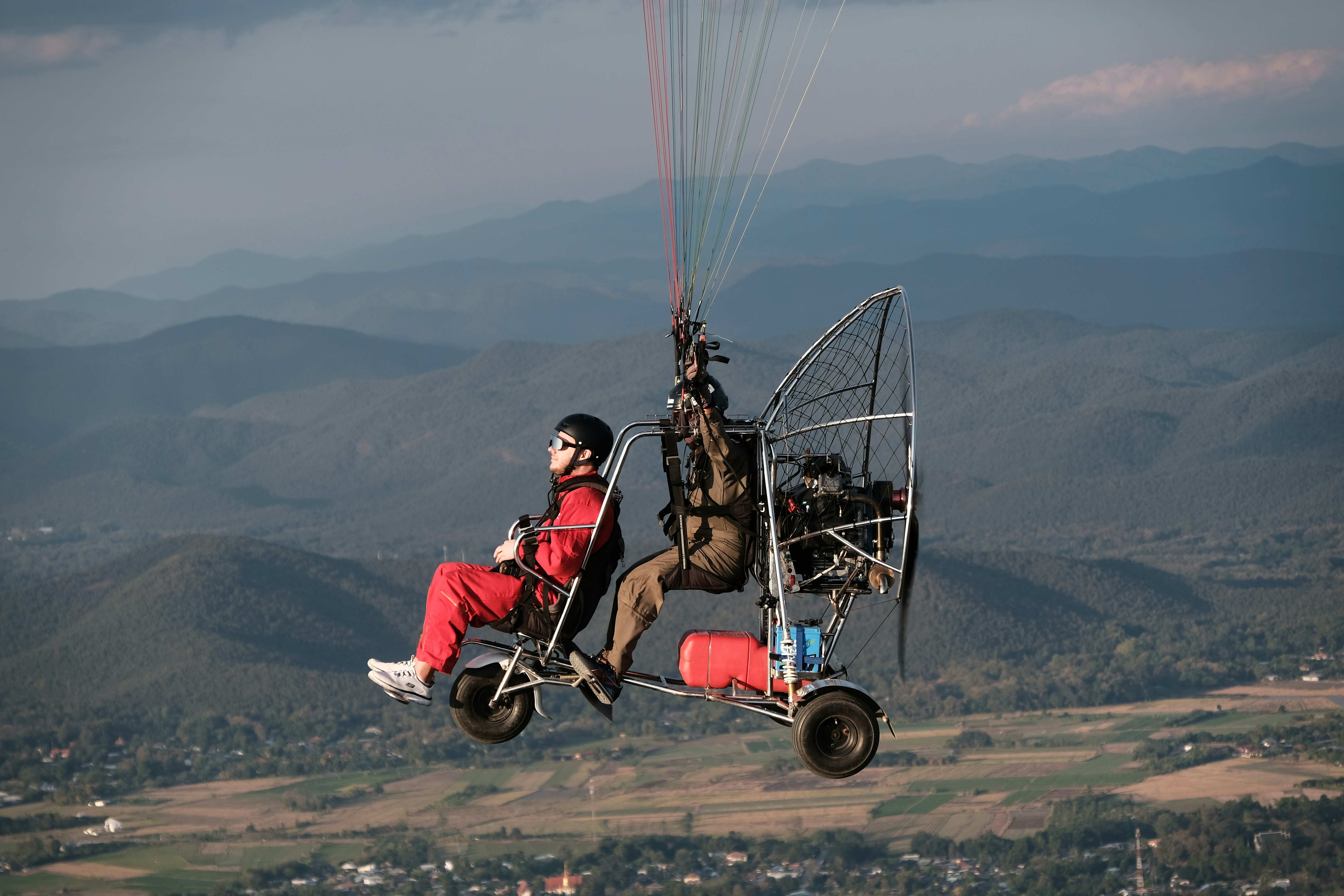 Zwei Personen paragleiten über eine malerische Landschaft