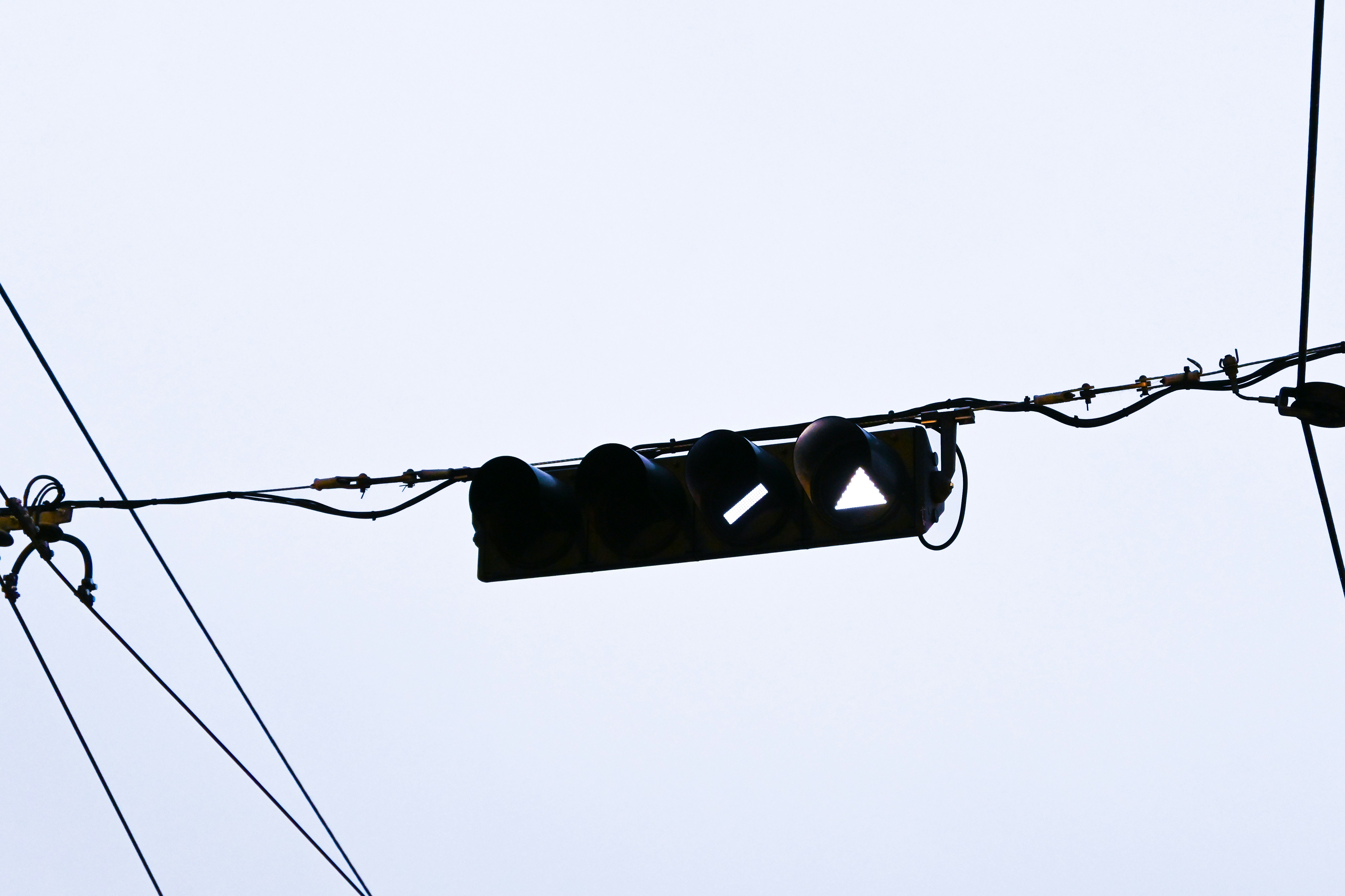 Traffic lights hanging from wires against a cloudy sky