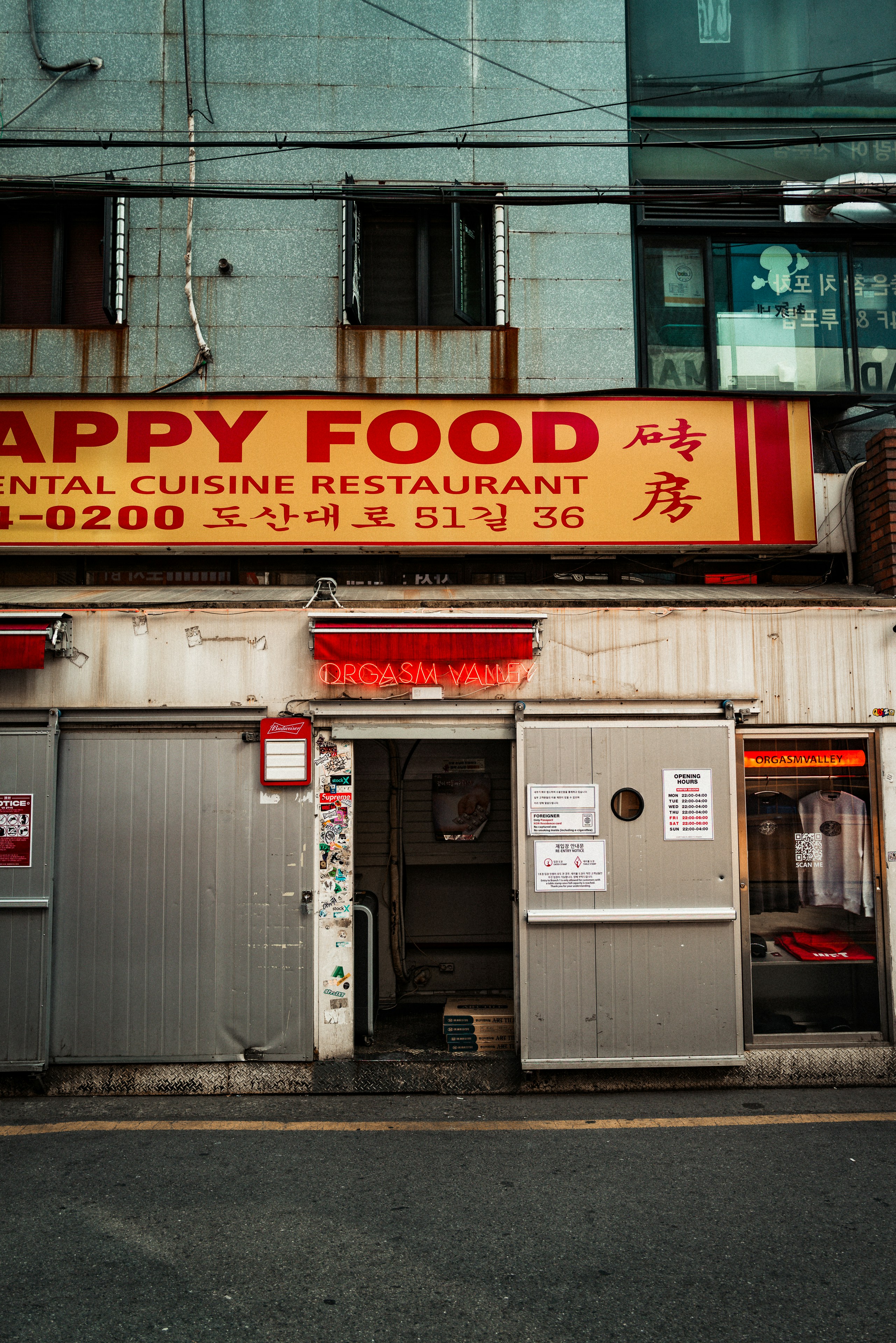 Entrada do restaurante com placas de neon e portas de metal.