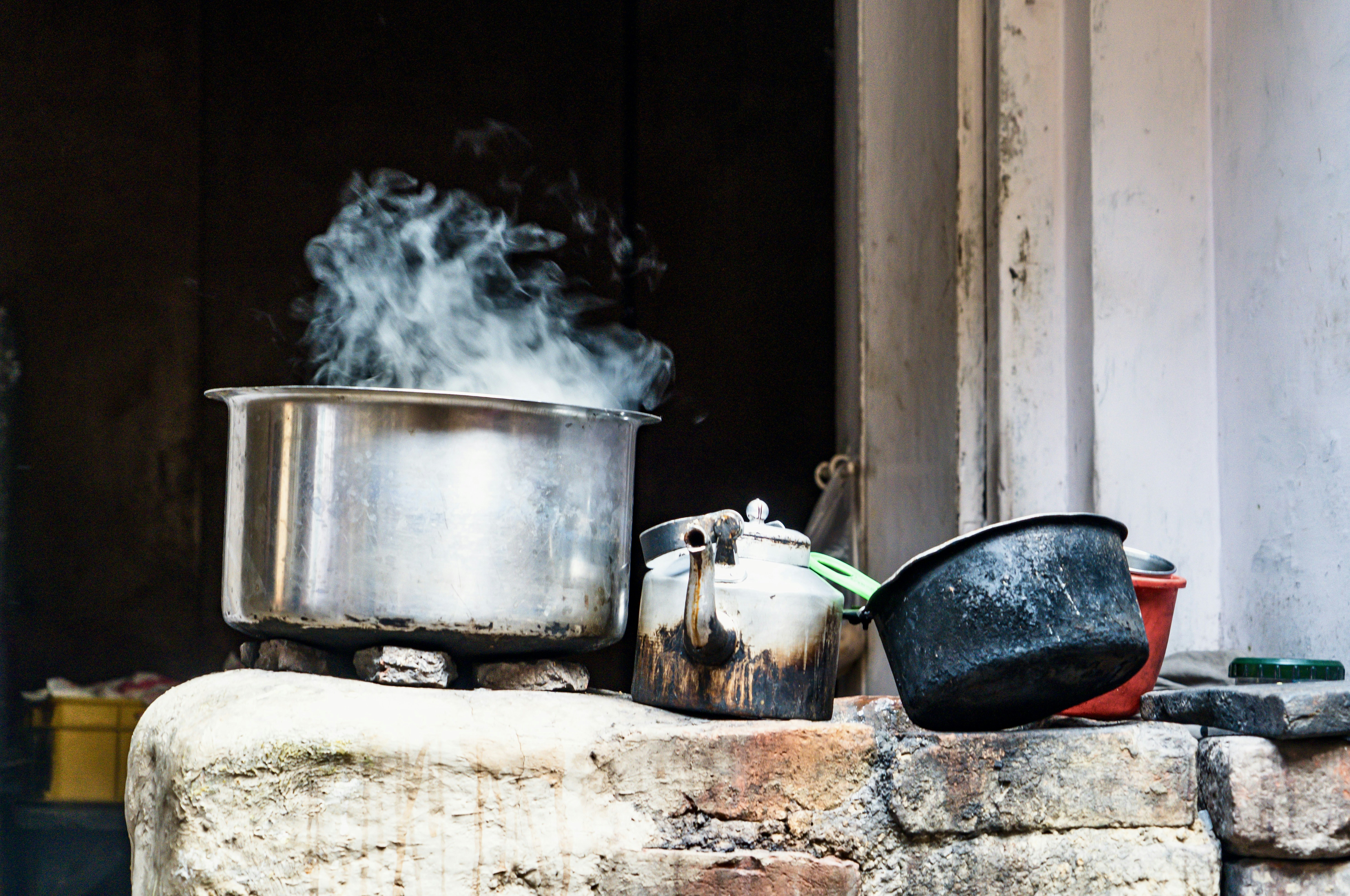 Steam rises from a pot on a rustic stove.