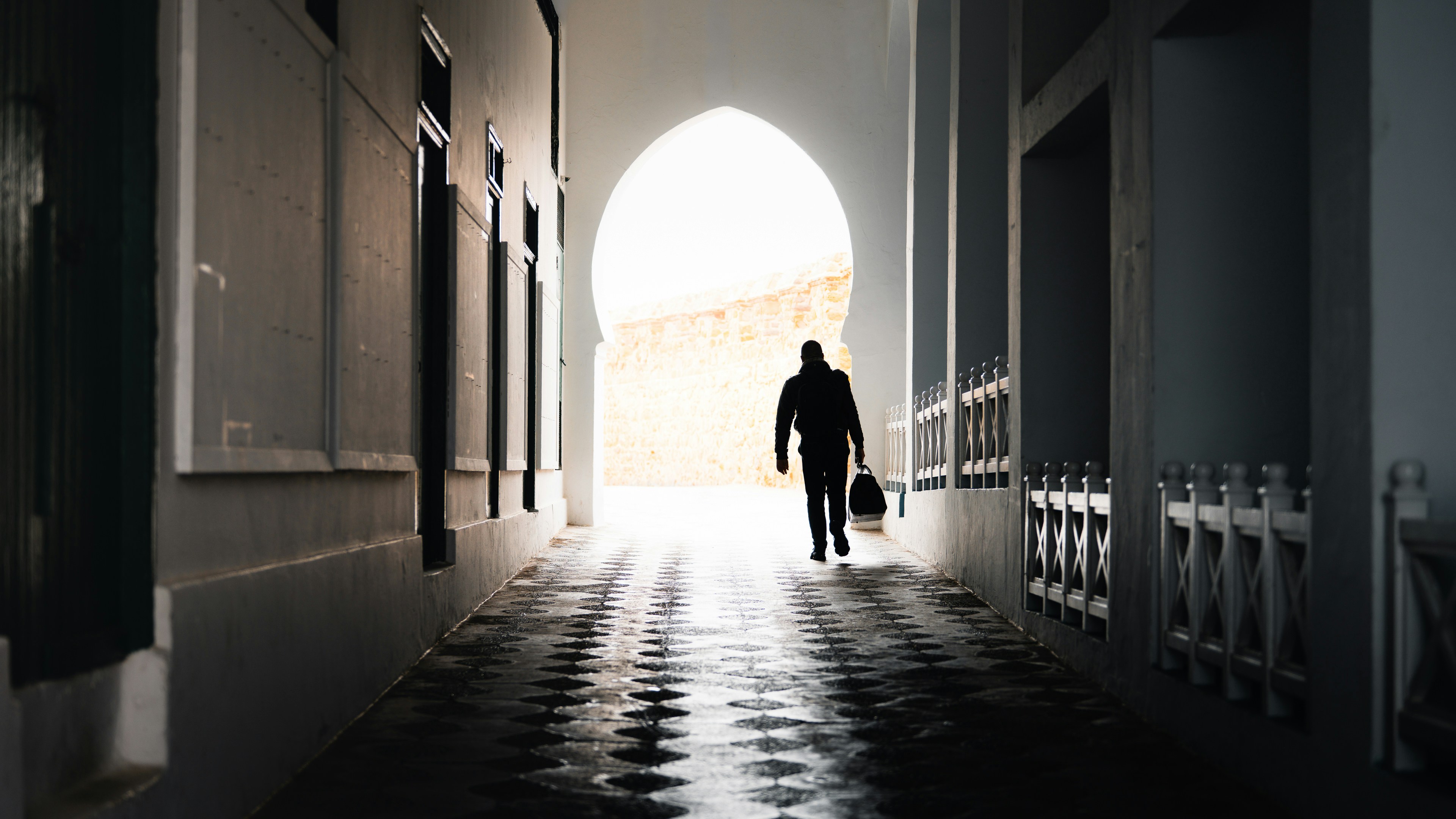 햇살이 가득한 골목길을 걷는 사람의 실루엣.