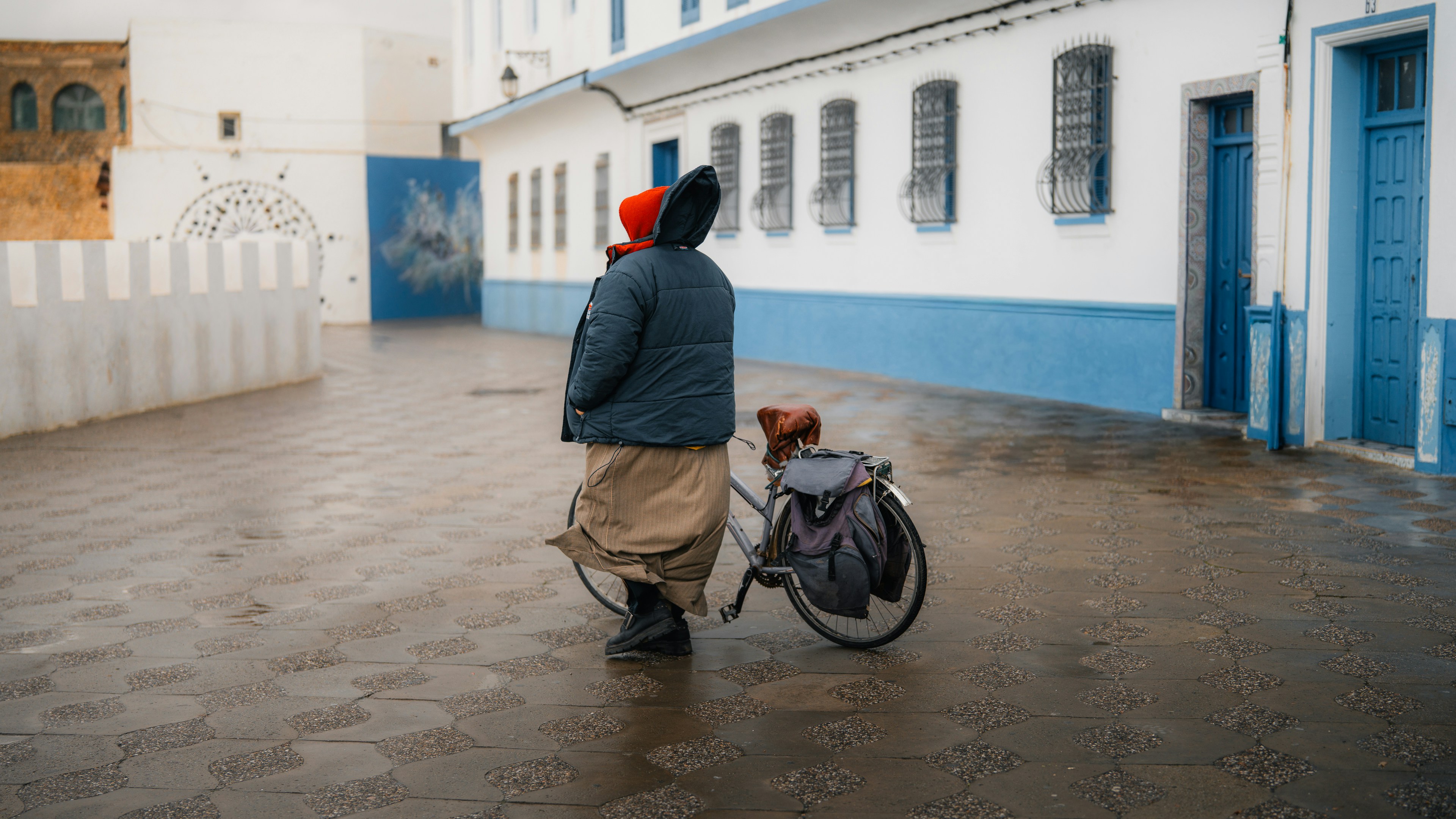 두 사람이 젖은 길을 자전거를 타고 걷고 있다.