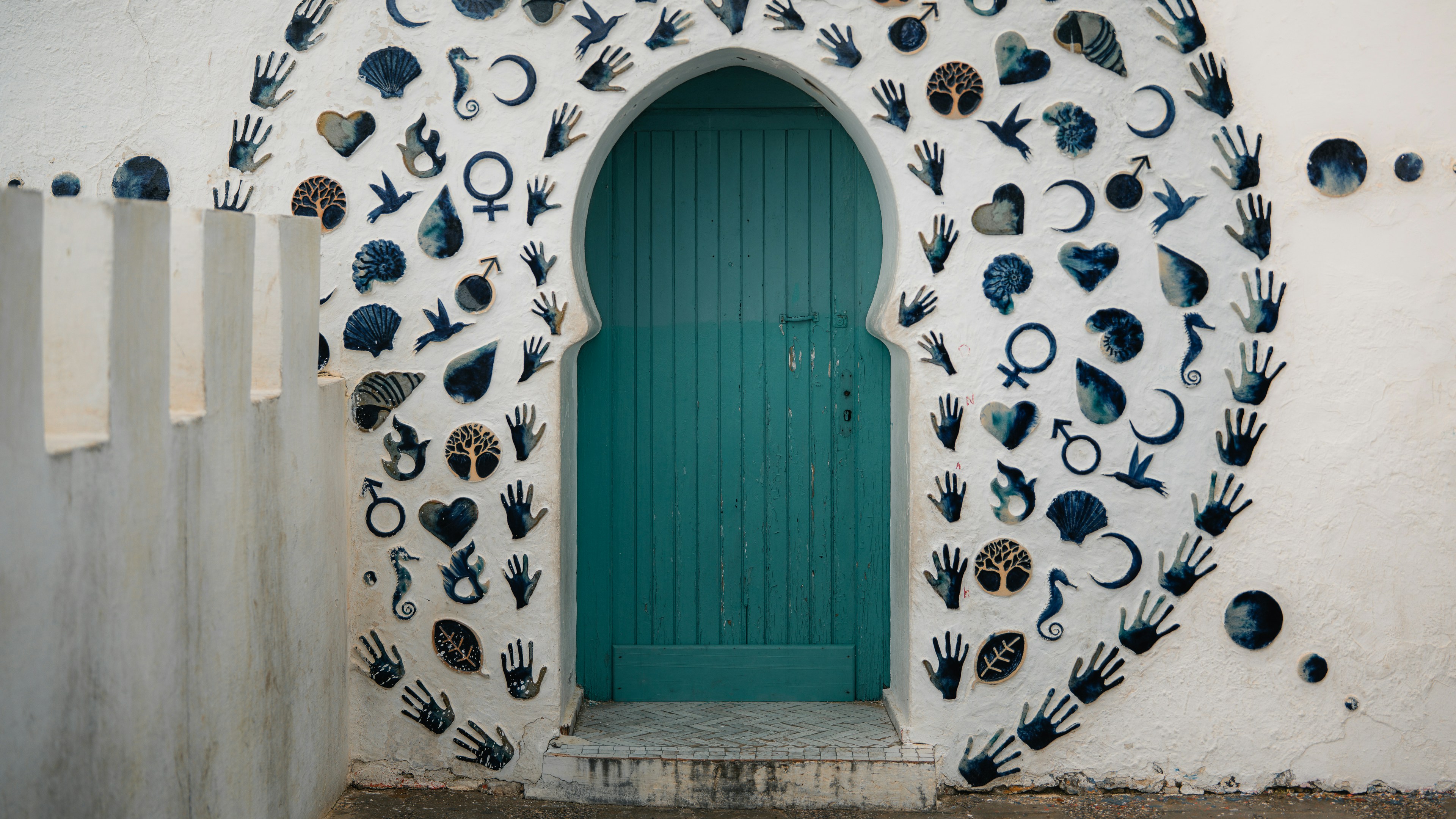 Ornate archway with teal door and decorative wall