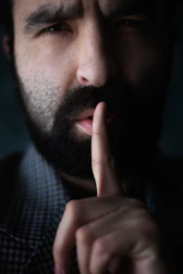 Man with beard holds finger to lips