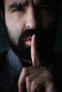 Man with beard holds finger to lips
