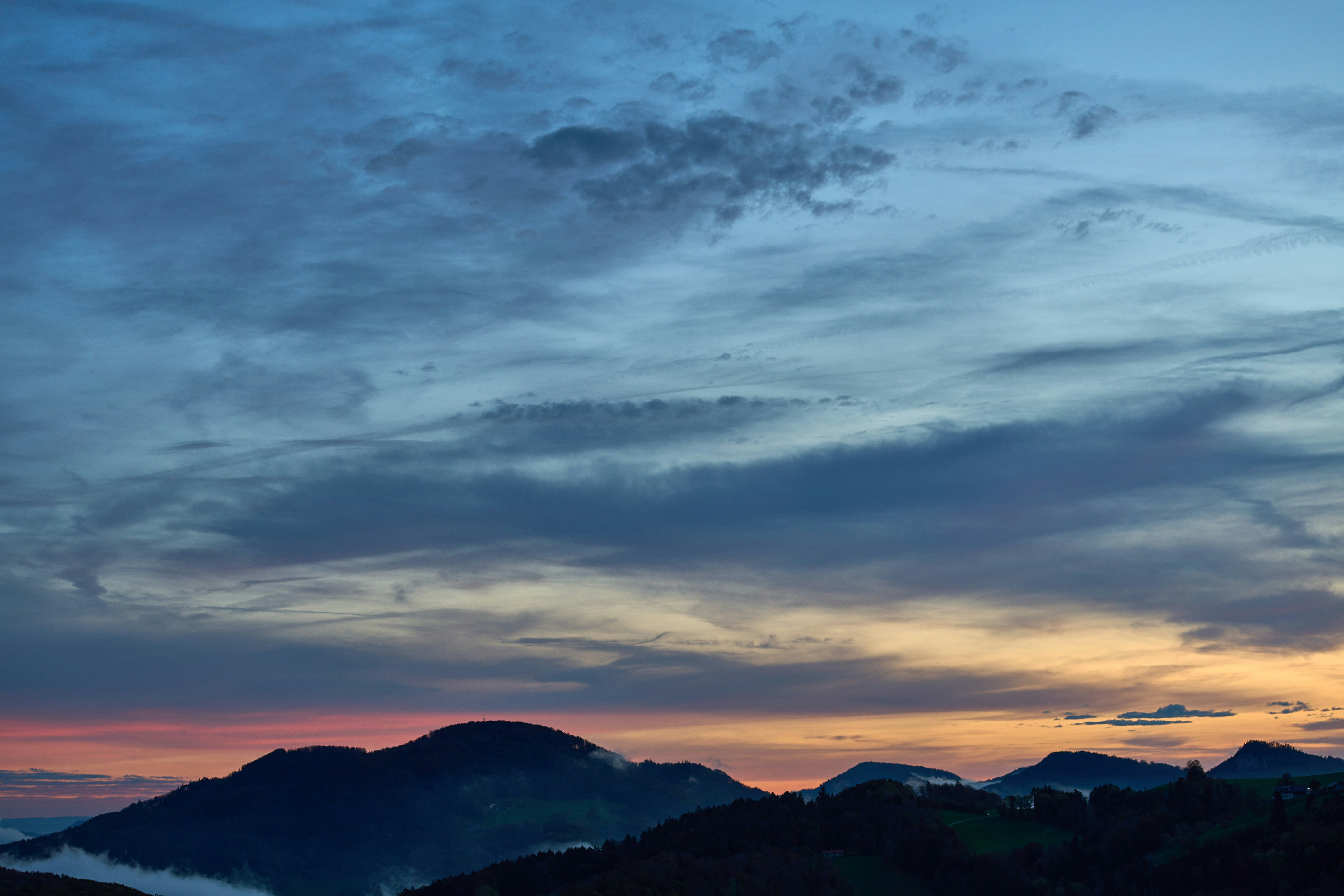 Dramatic clouds over silhouetted mountains at dusk