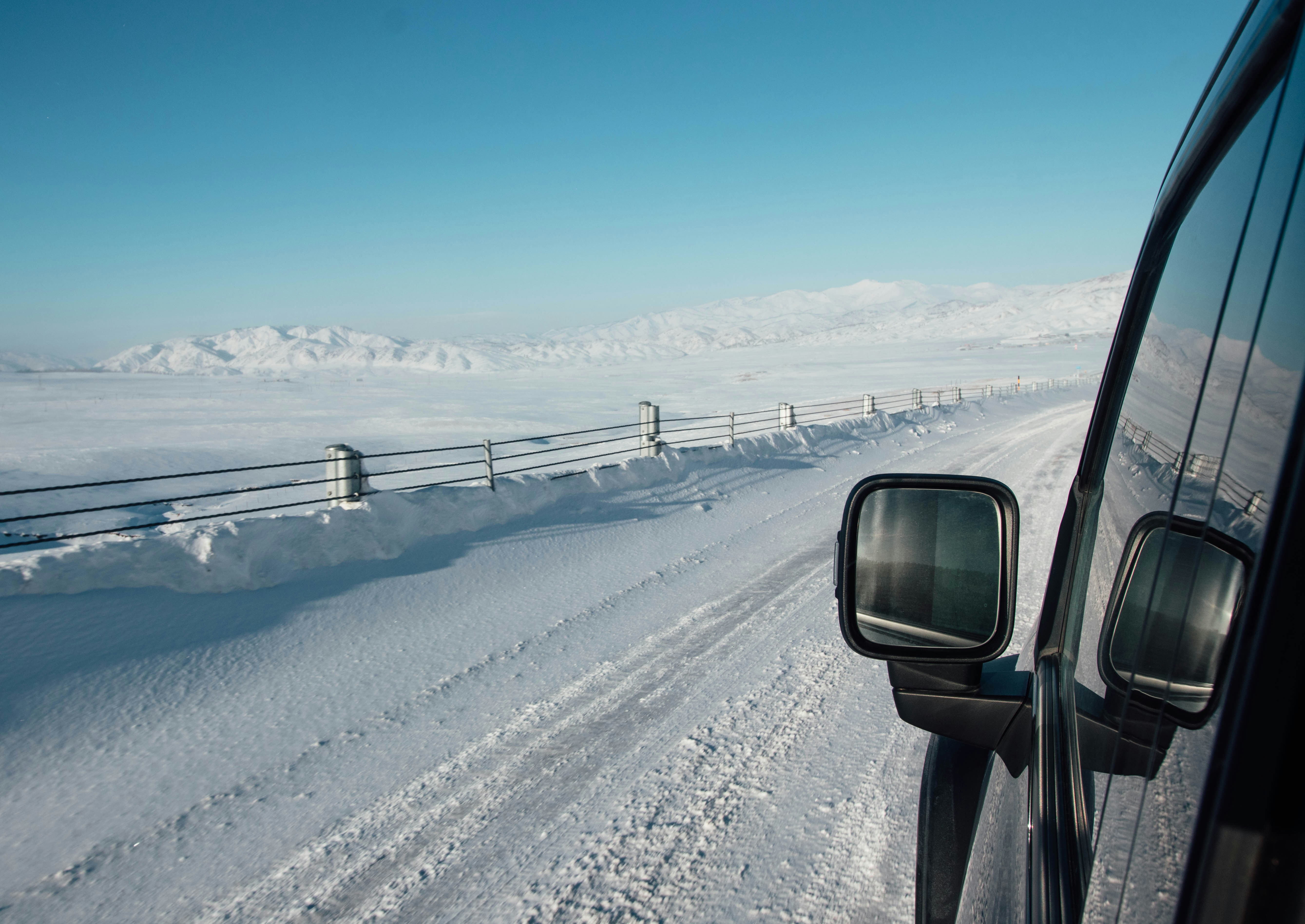 Driving on a snowy road with mountains in distance