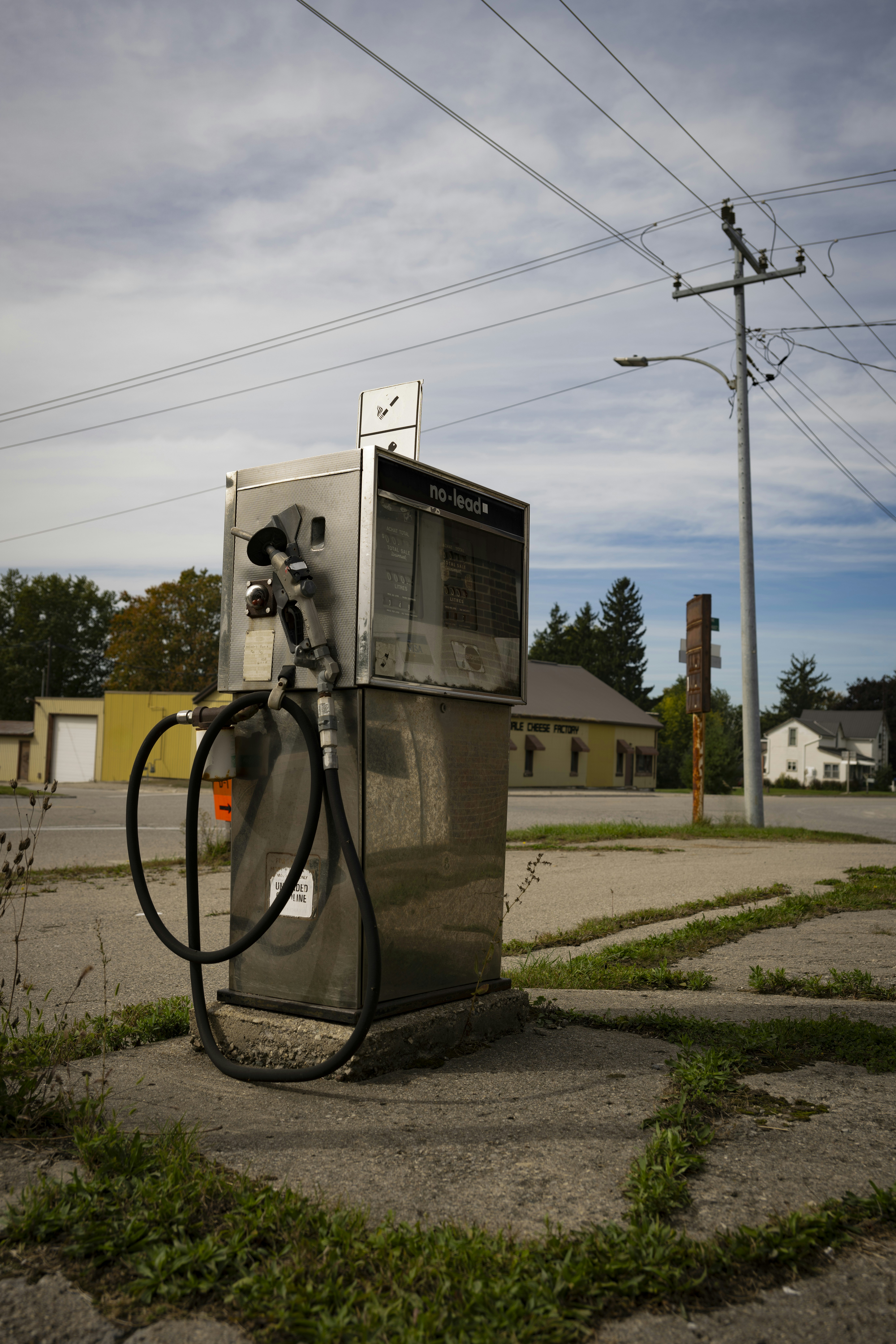 An old gas pump stands abandoned near a road.