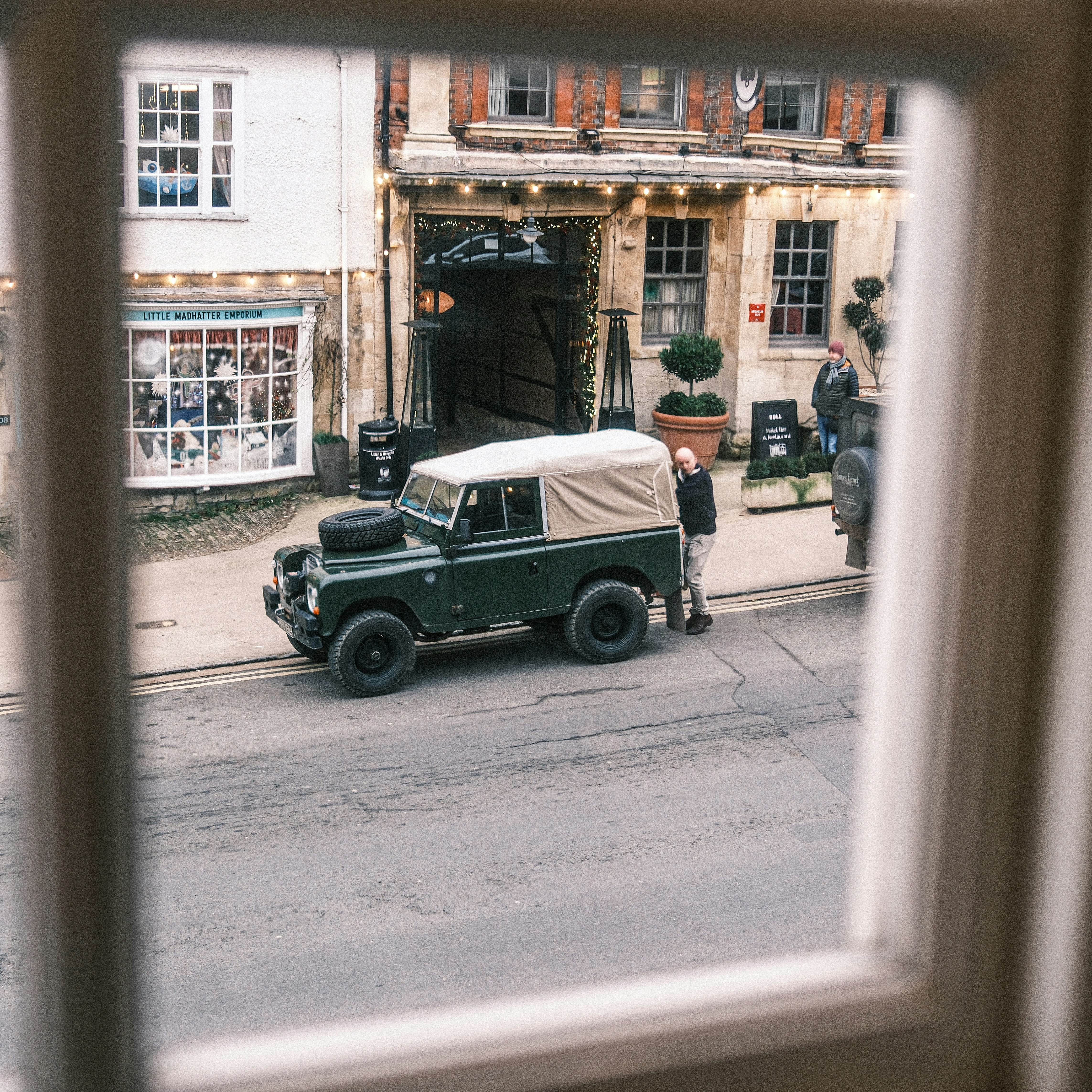 Vintage green land rover parked outside building