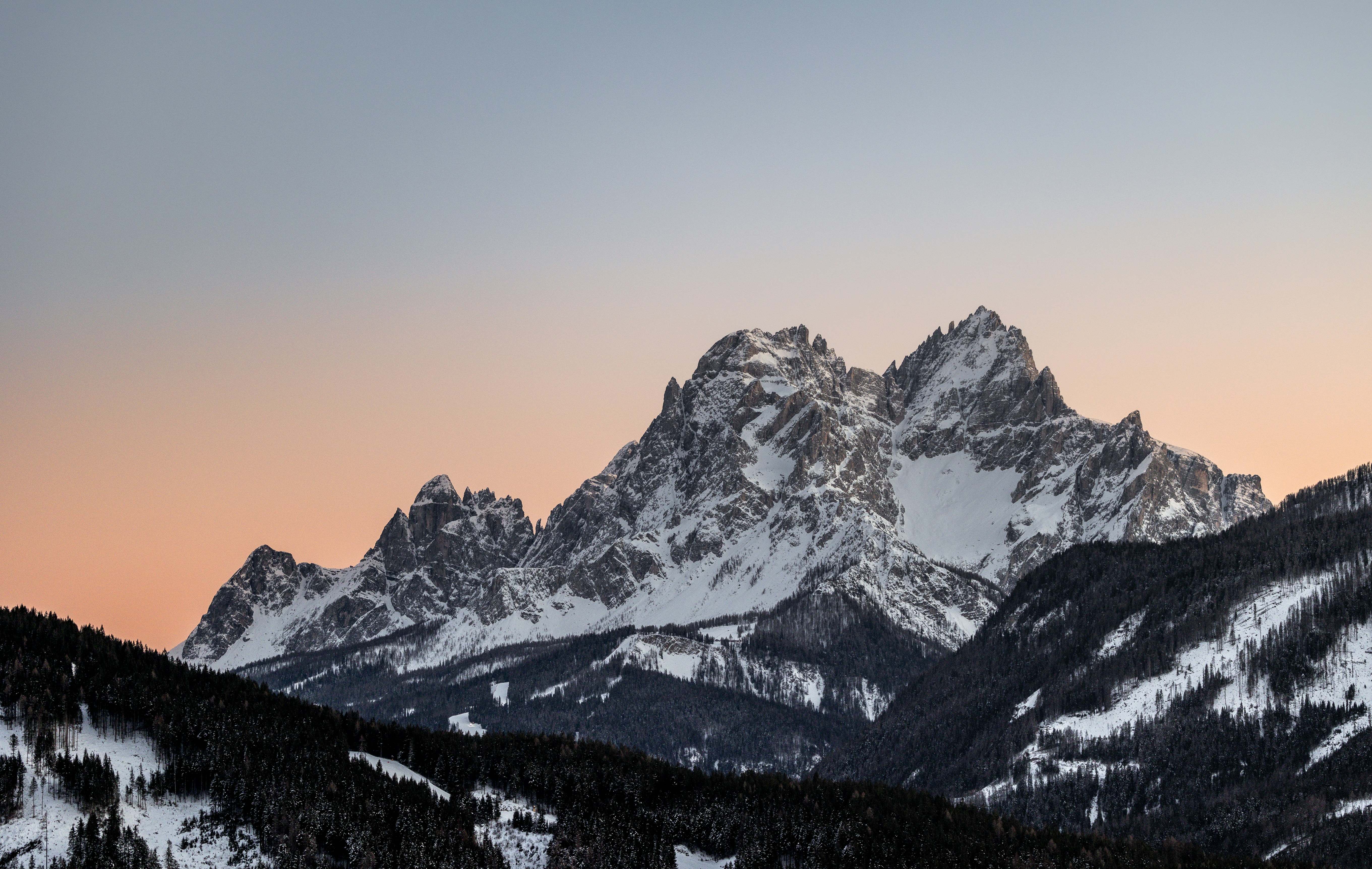 Snow-capped mountain peaks against a pastel sky