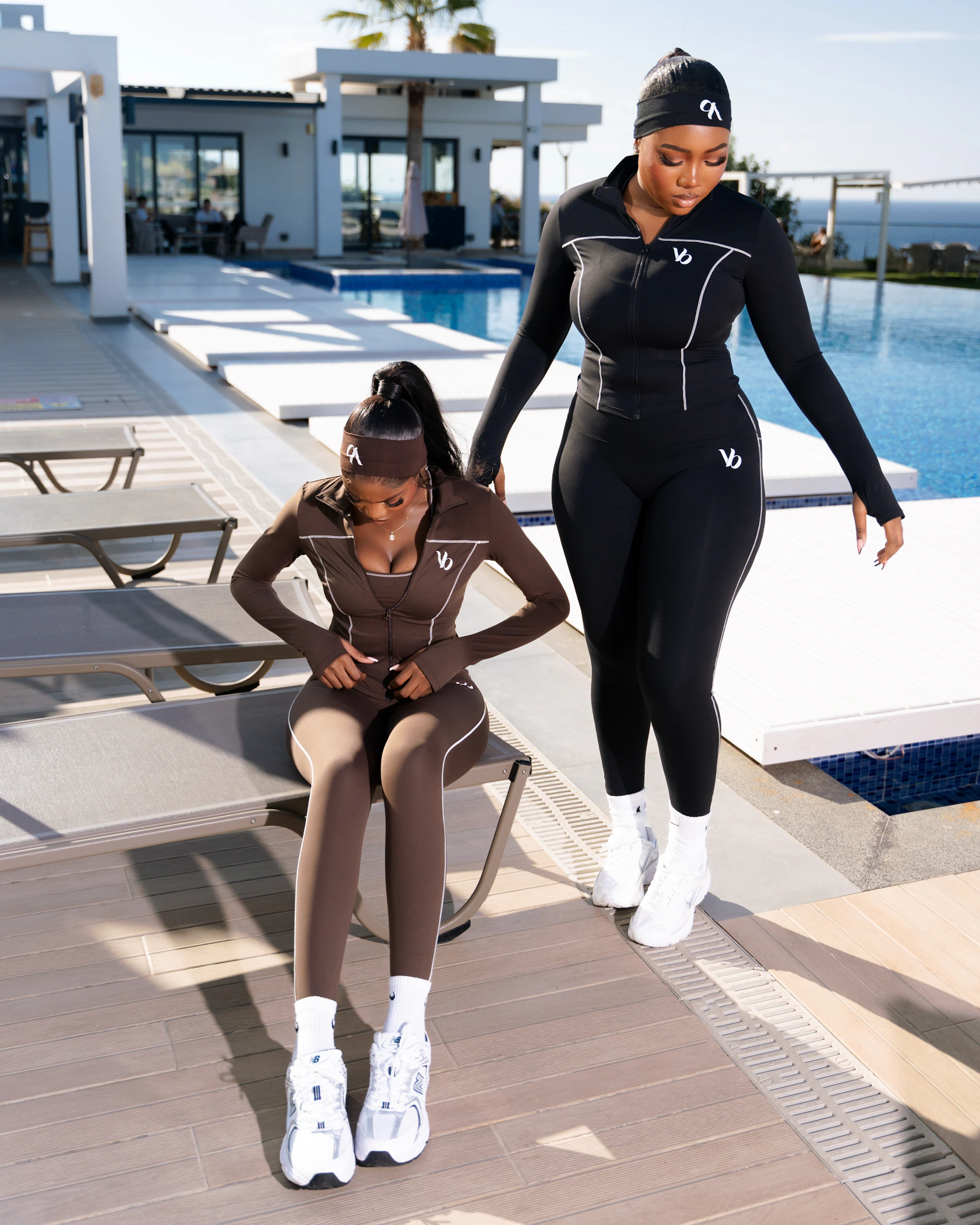 Two women in athletic wear by a pool