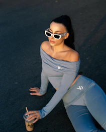 Woman in sunglasses and off-the-shoulder top with coffee