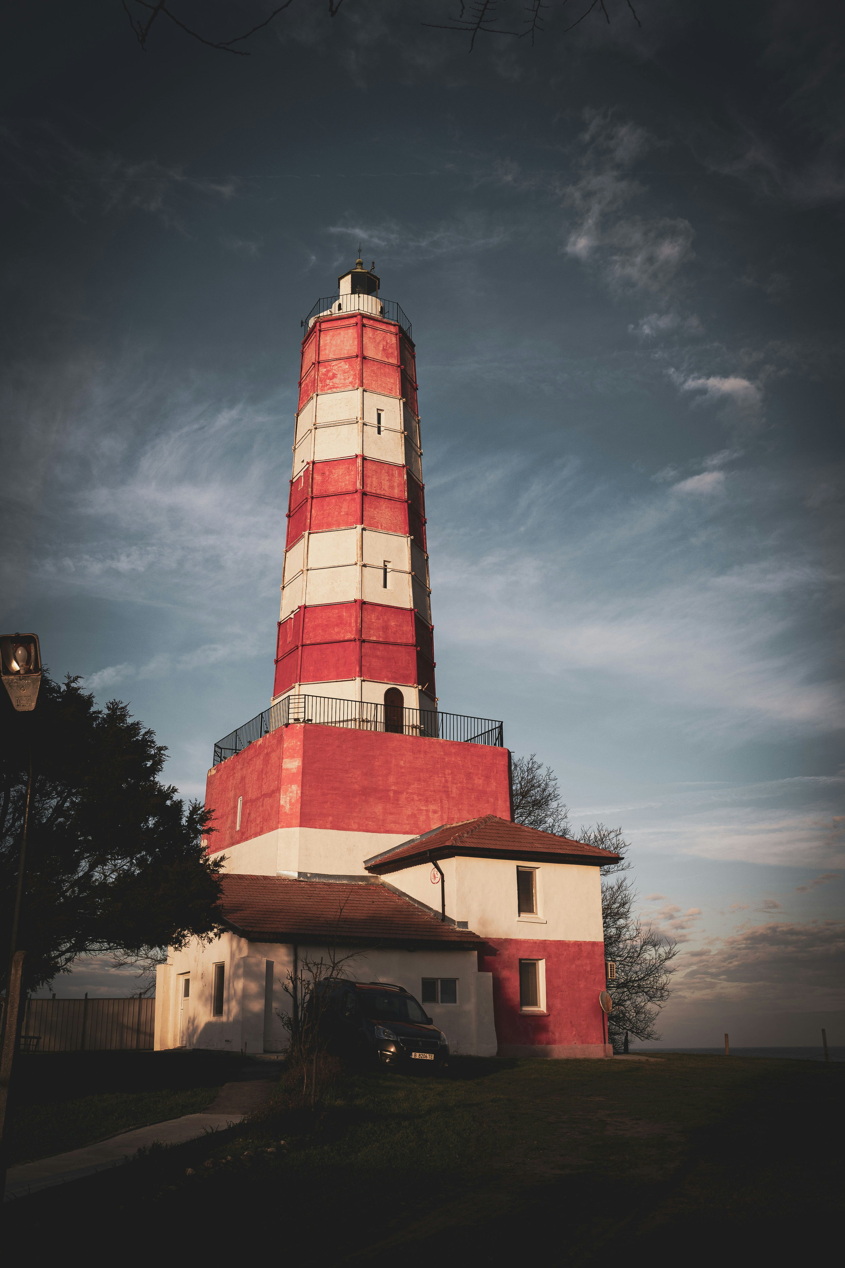 Rot-weiß gestreifter Leuchtturm vor einem wolkigen Himmel